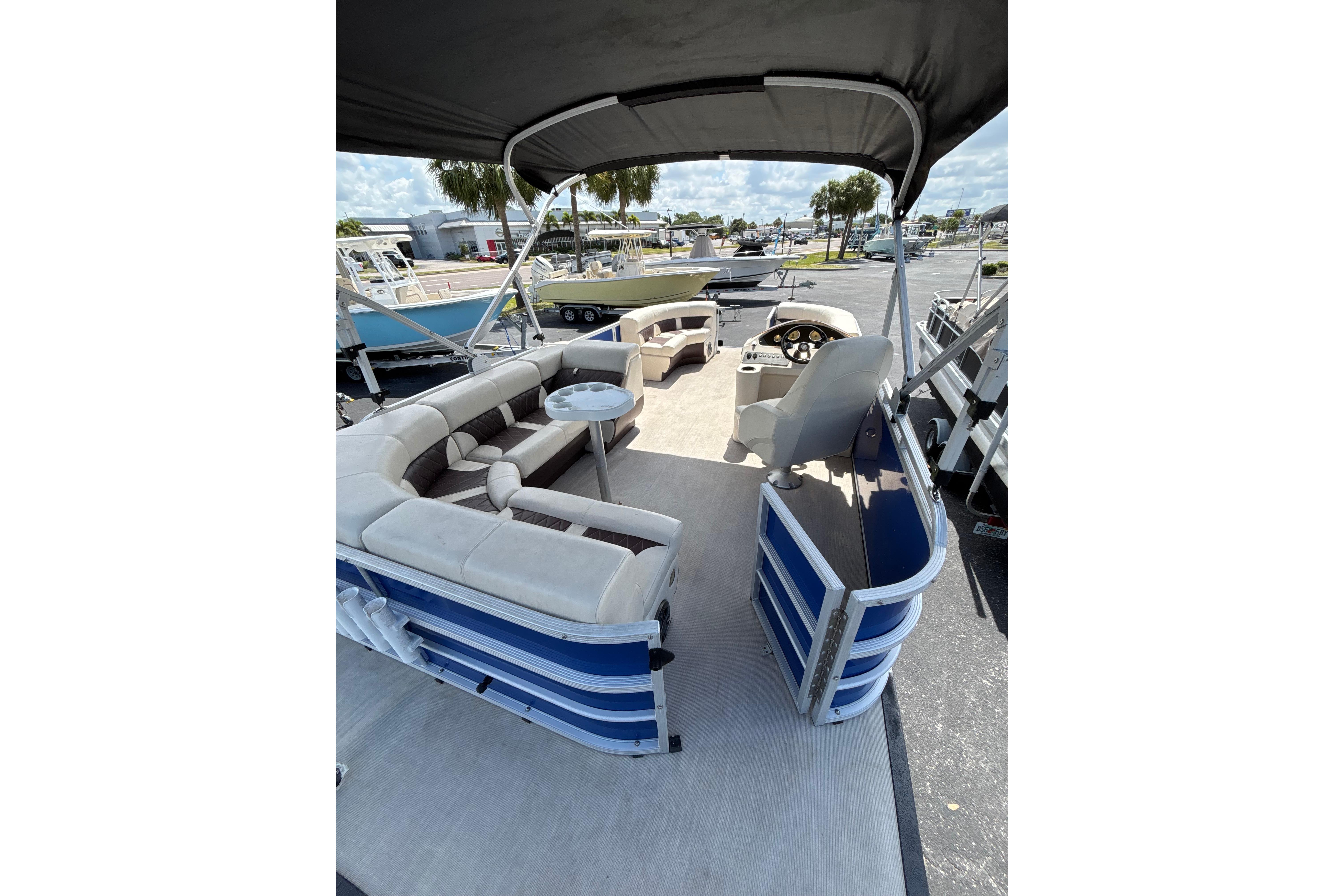 2022 Lexington 323 pontoon boat interior with seating and helm, parked outdoors.