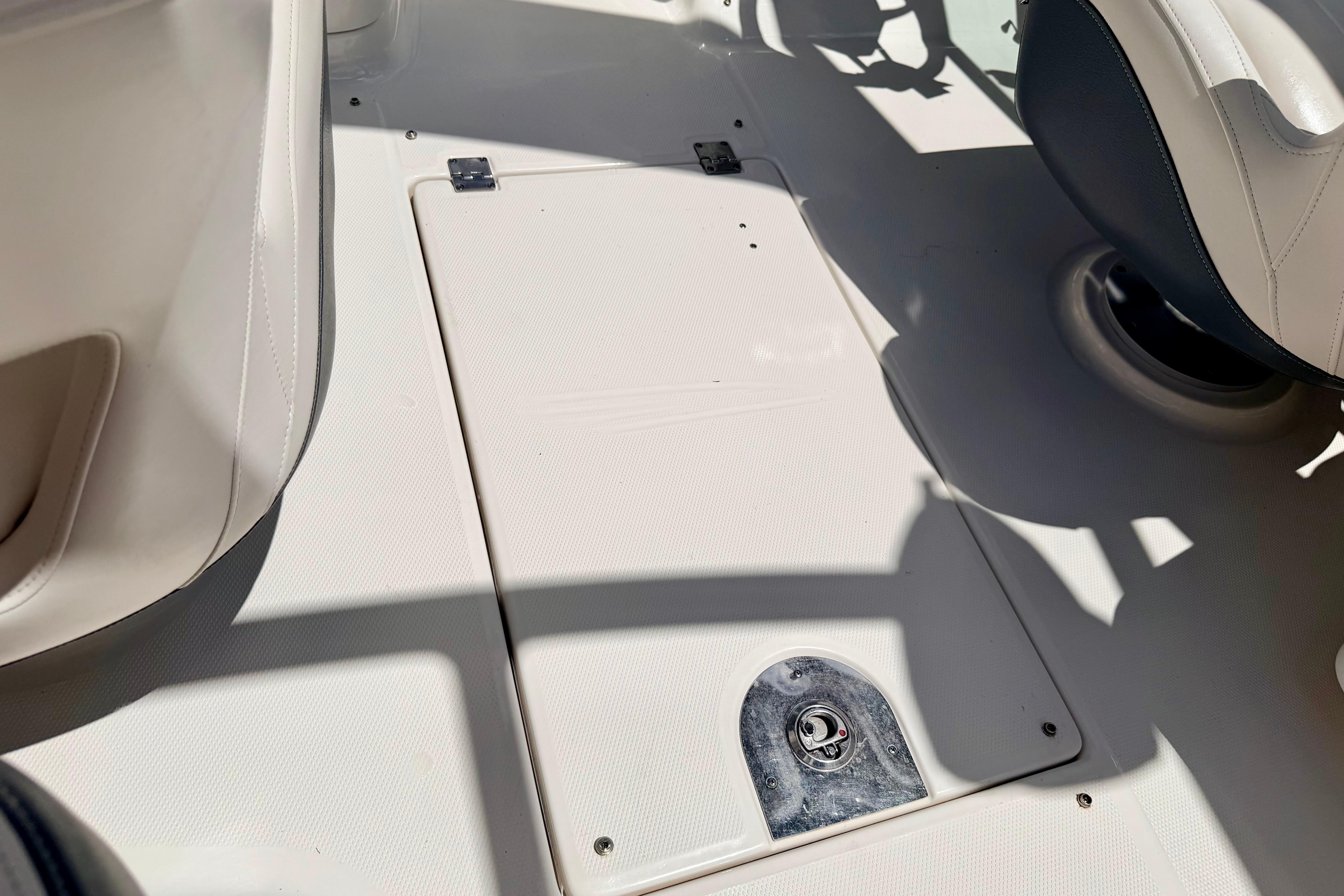 2015 Chaparral Sunesta 264 boat interior, featuring a storage compartment and seating area.