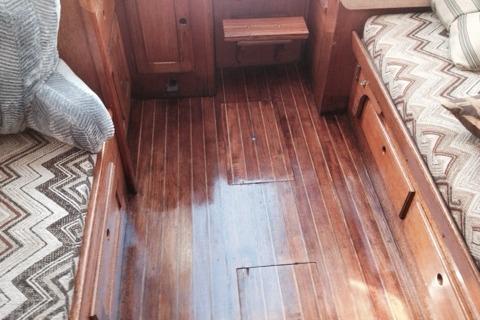 Interior of 1980 Sloop 27.7 Bristol with polished wooden flooring and patterned cushions.