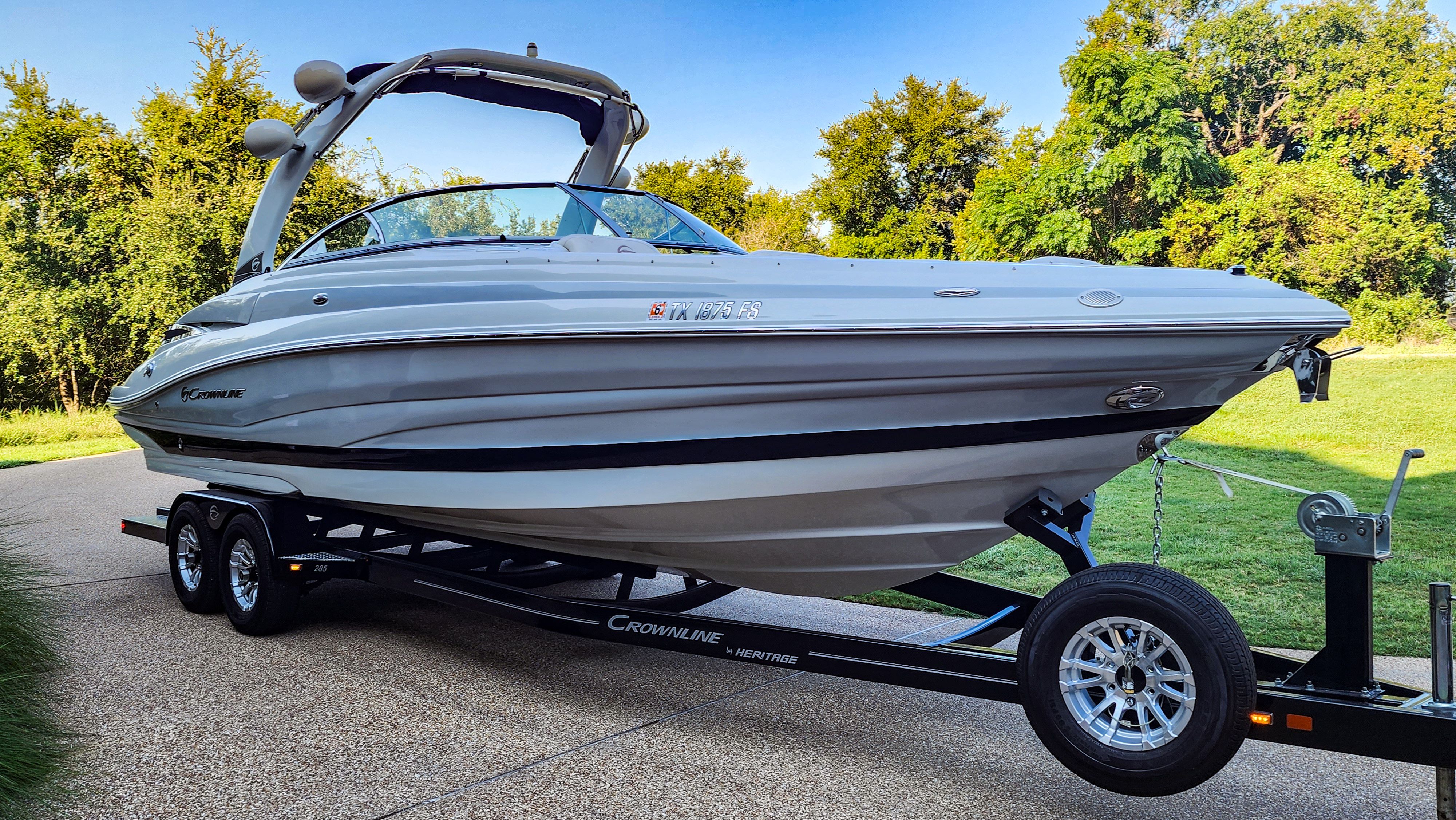 2017 Crownline 285SS on a trailer, surrounded by trees and grass.