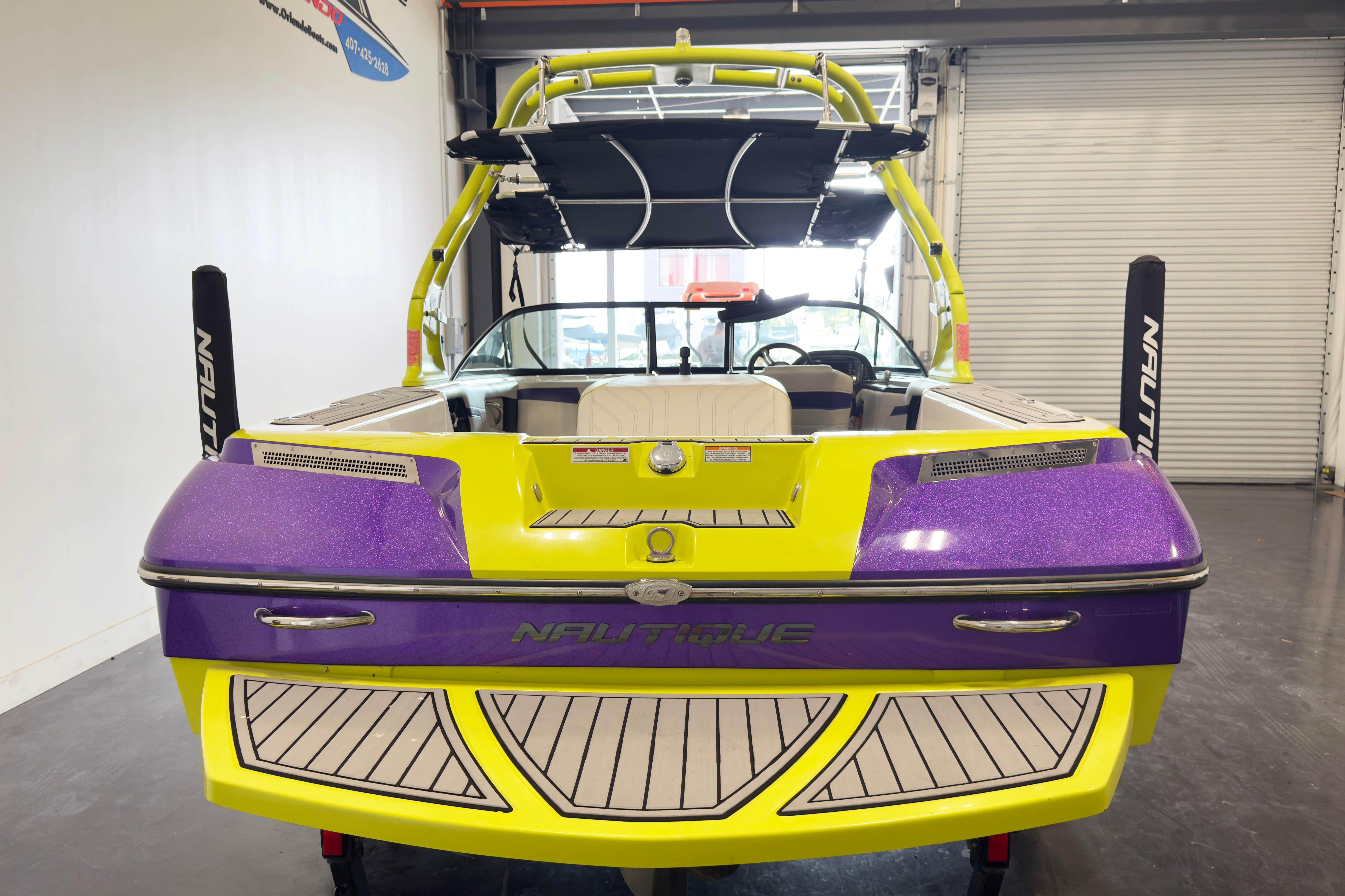 2014 Nautique Ski Nautique 200 Closed Bow in vibrant yellow and purple, rear view in garage.