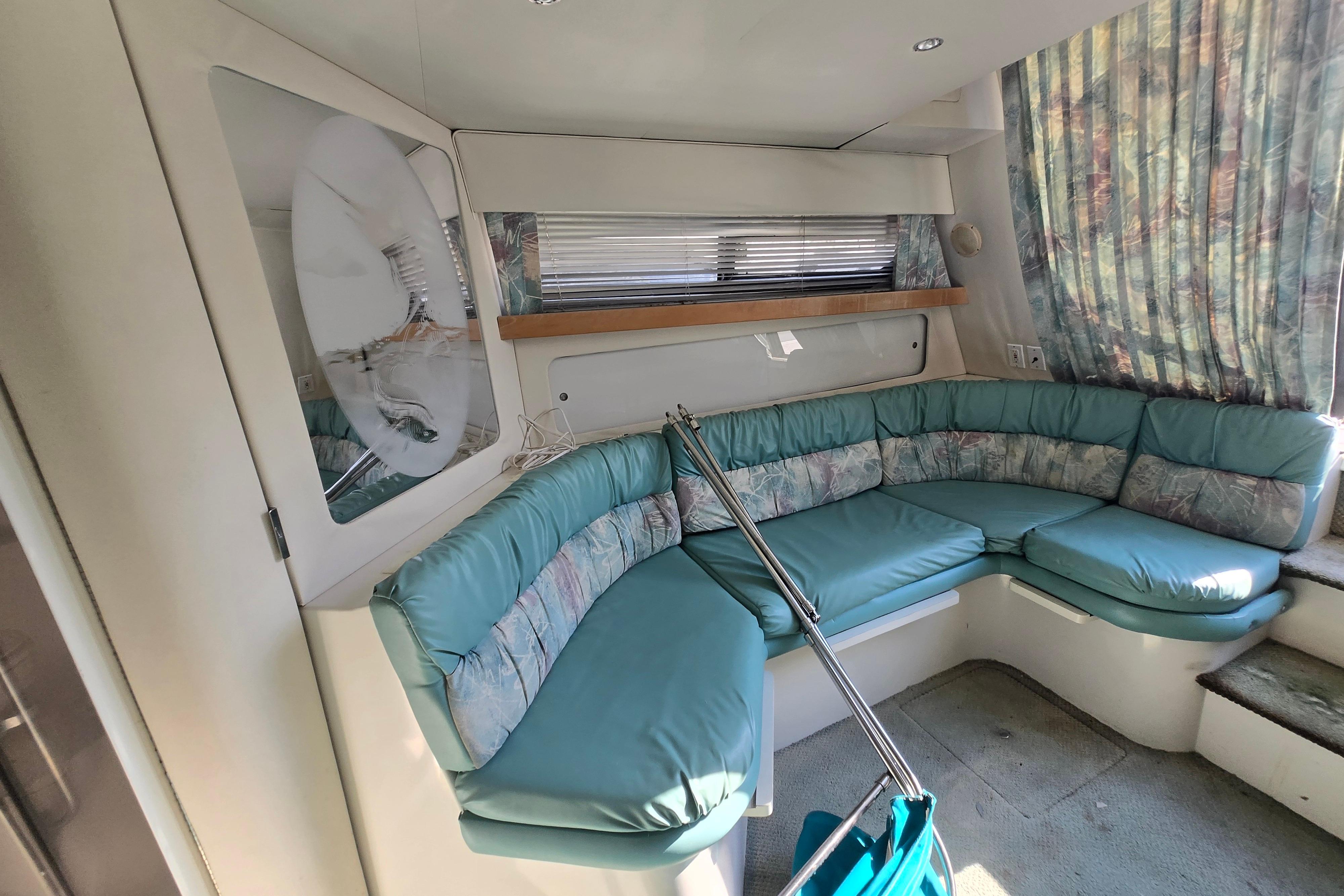 Interior of a 1994 Carver 380 Santego yacht with teal seating and patterned curtains.