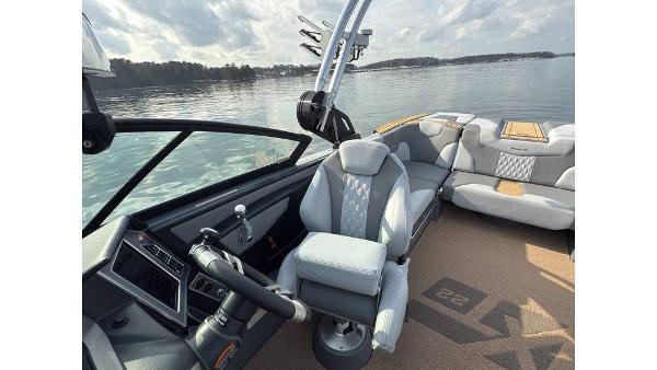 2023 MasterCraft XT22 boat interior with sleek seating and modern dashboard on a calm lake.