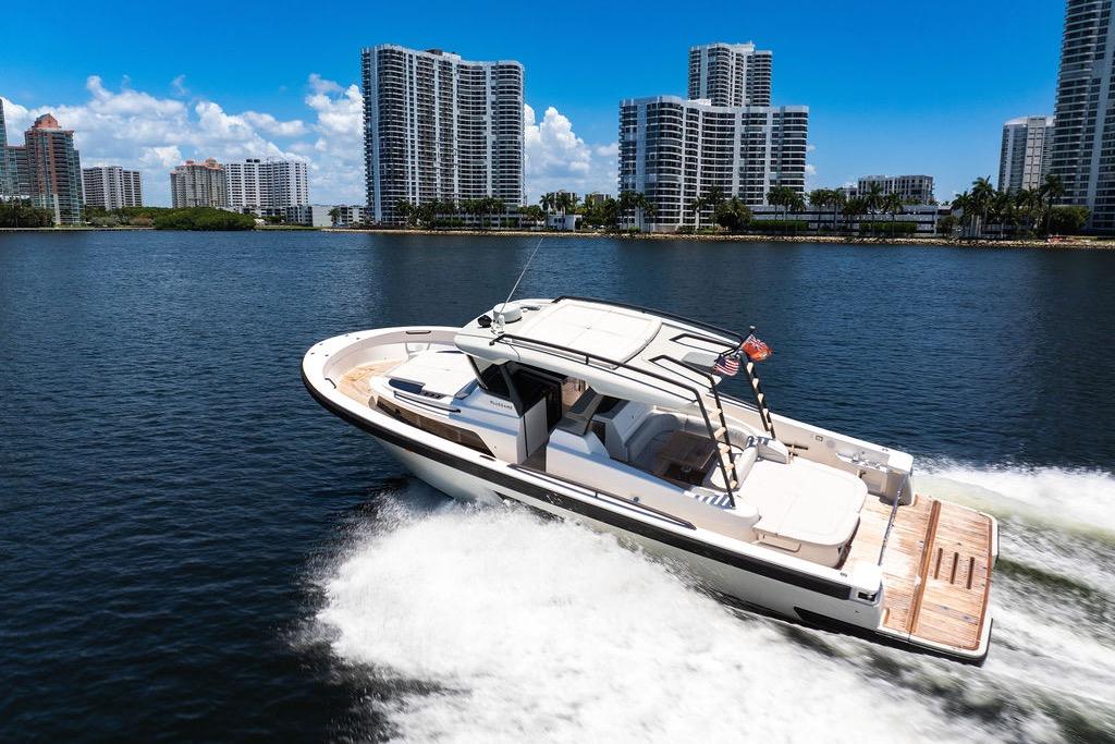 2021 Bluegame BG 42 yacht cruising near city skyline on a sunny day.
