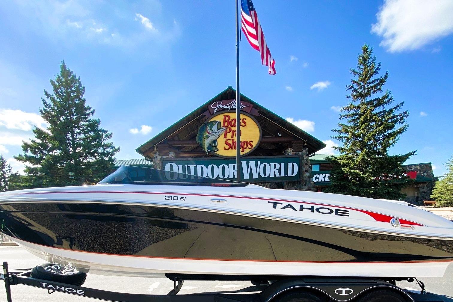 2023 Tahoe 210 Si Limited boat displayed at Outdoor World with American flag.
