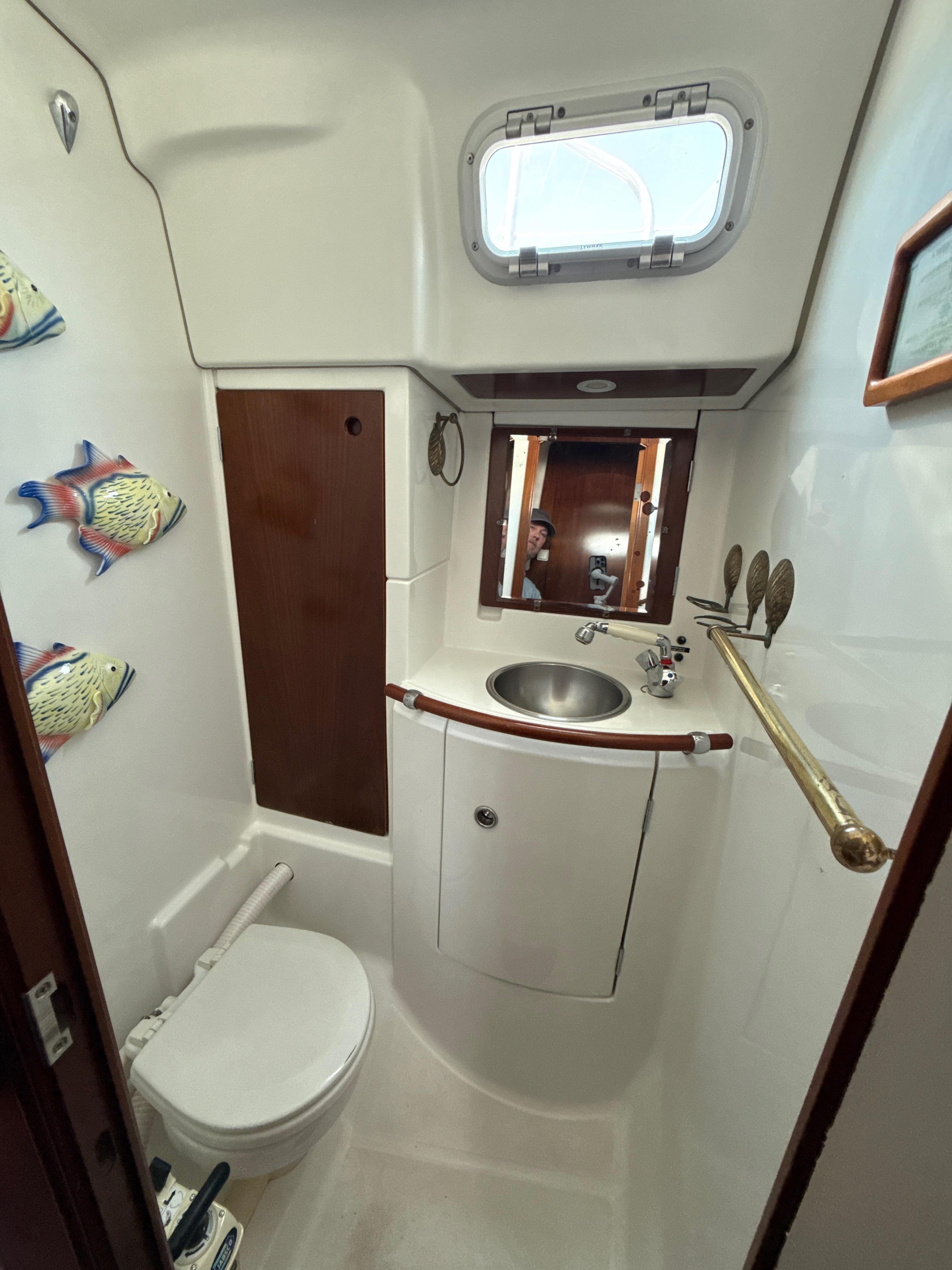 Bathroom interior of a 1997 Beneteau 50 yacht, featuring sink, toilet, and nautical decor.
