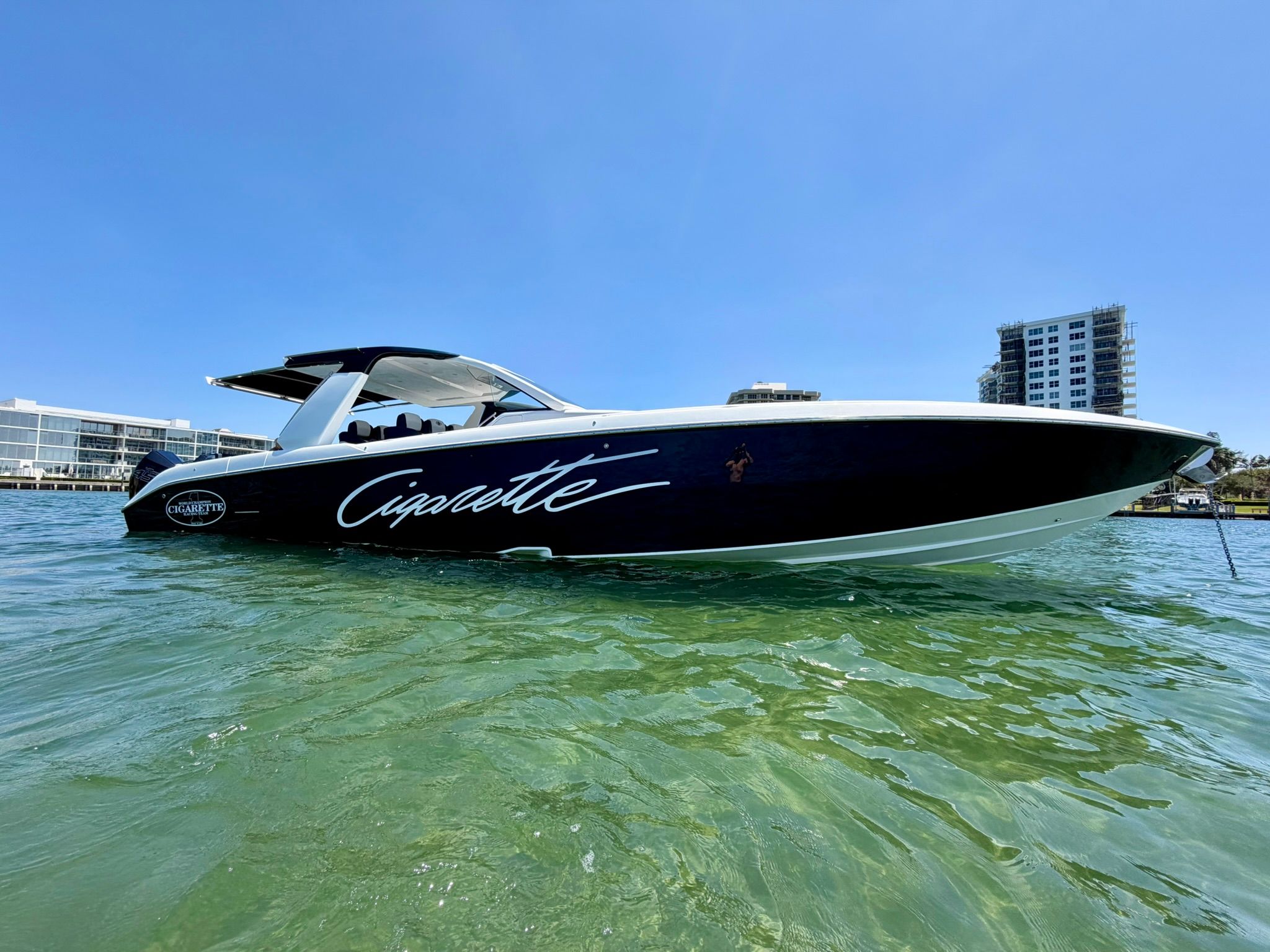 A Cigarette Nighthawk 2022 boat on calm water with an urban backdrop.