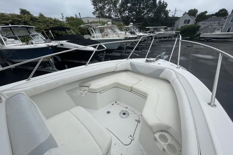 2012 Boston Whaler 250 Outrage boat with spacious seating, docked among other boats.