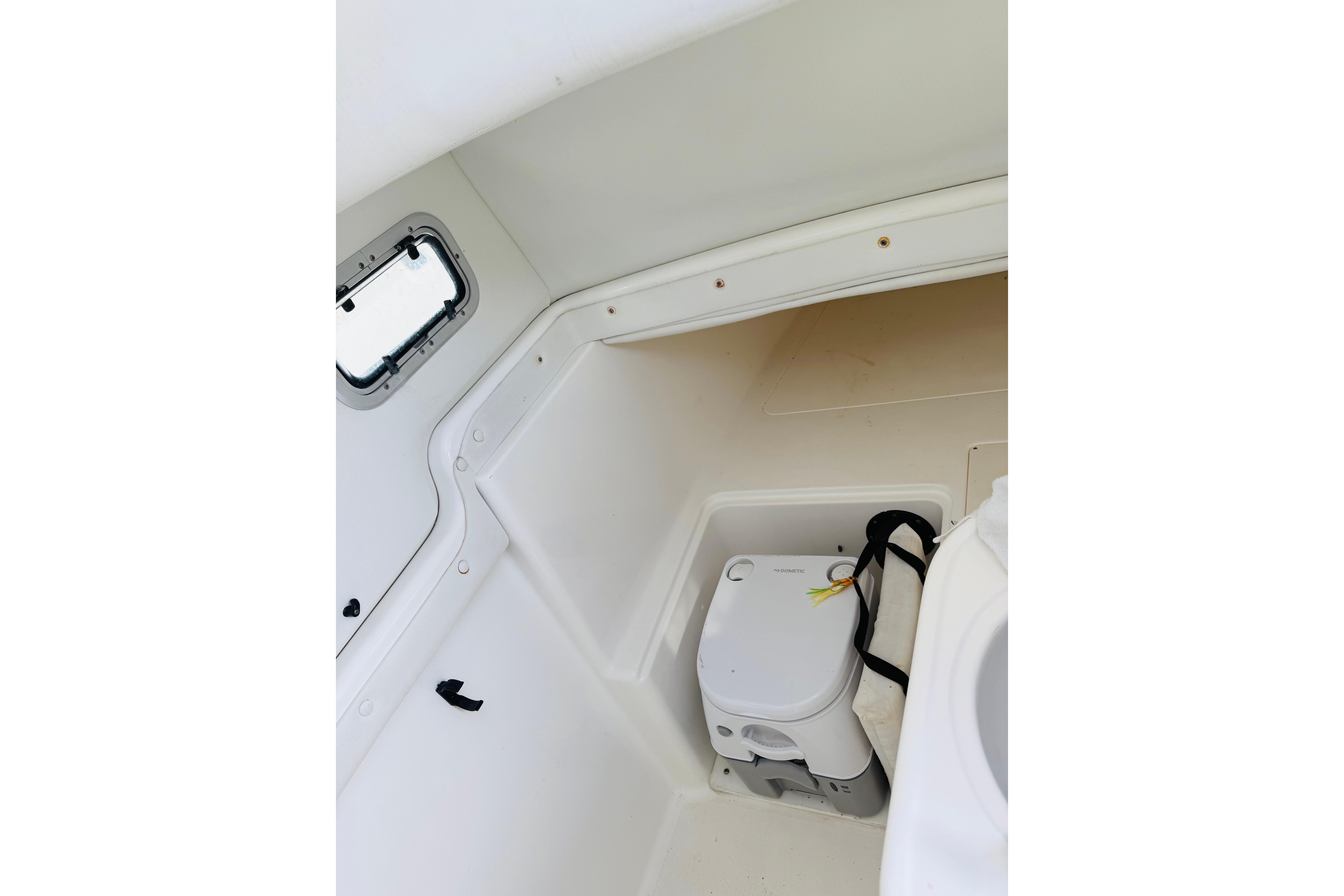 Interior of 2005 Century 3200 Center Console boat with compact toilet and window.