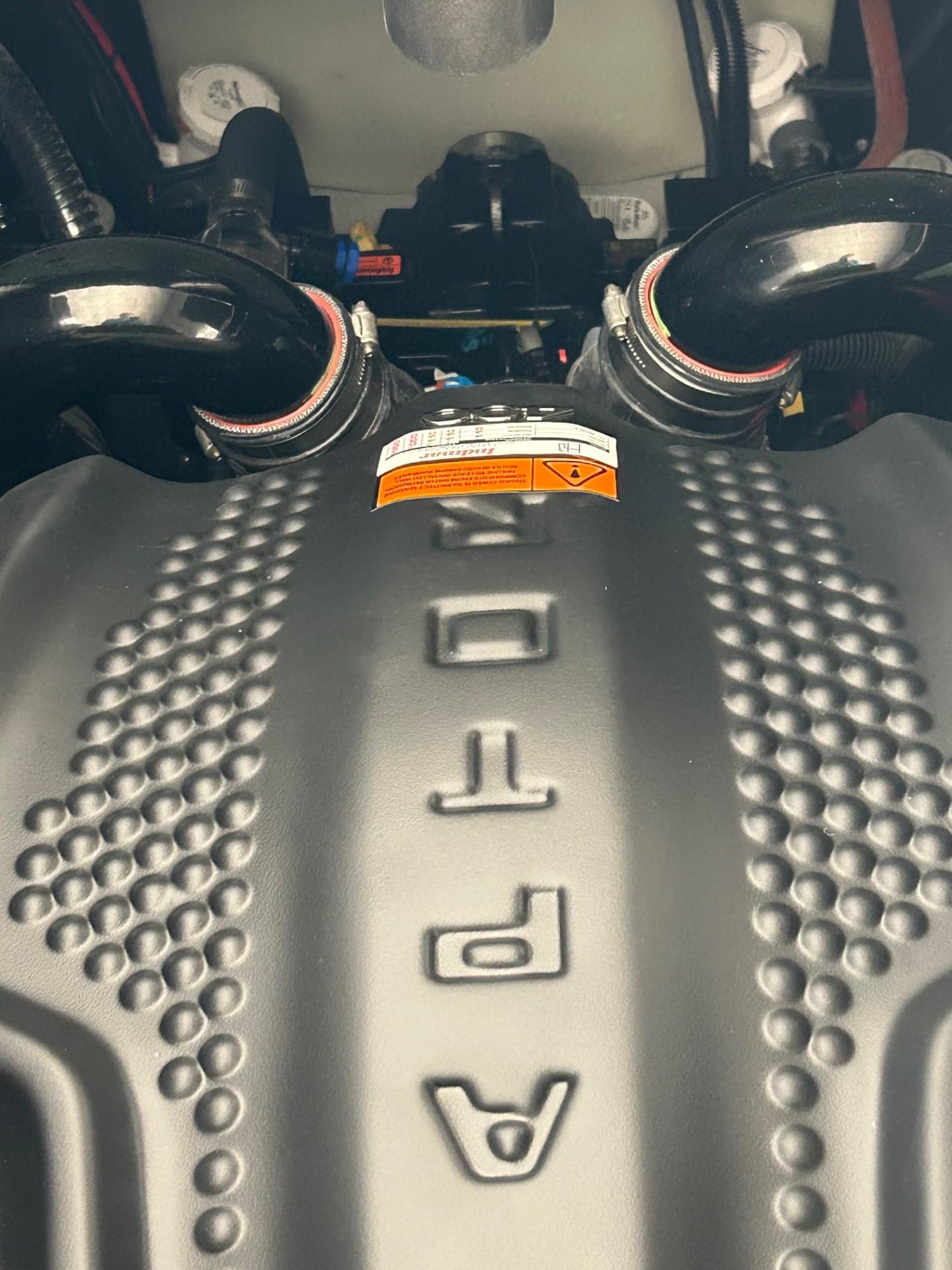 Close-up of 2024 MB F22 Tomcat engine cover with textured design and visible hoses.