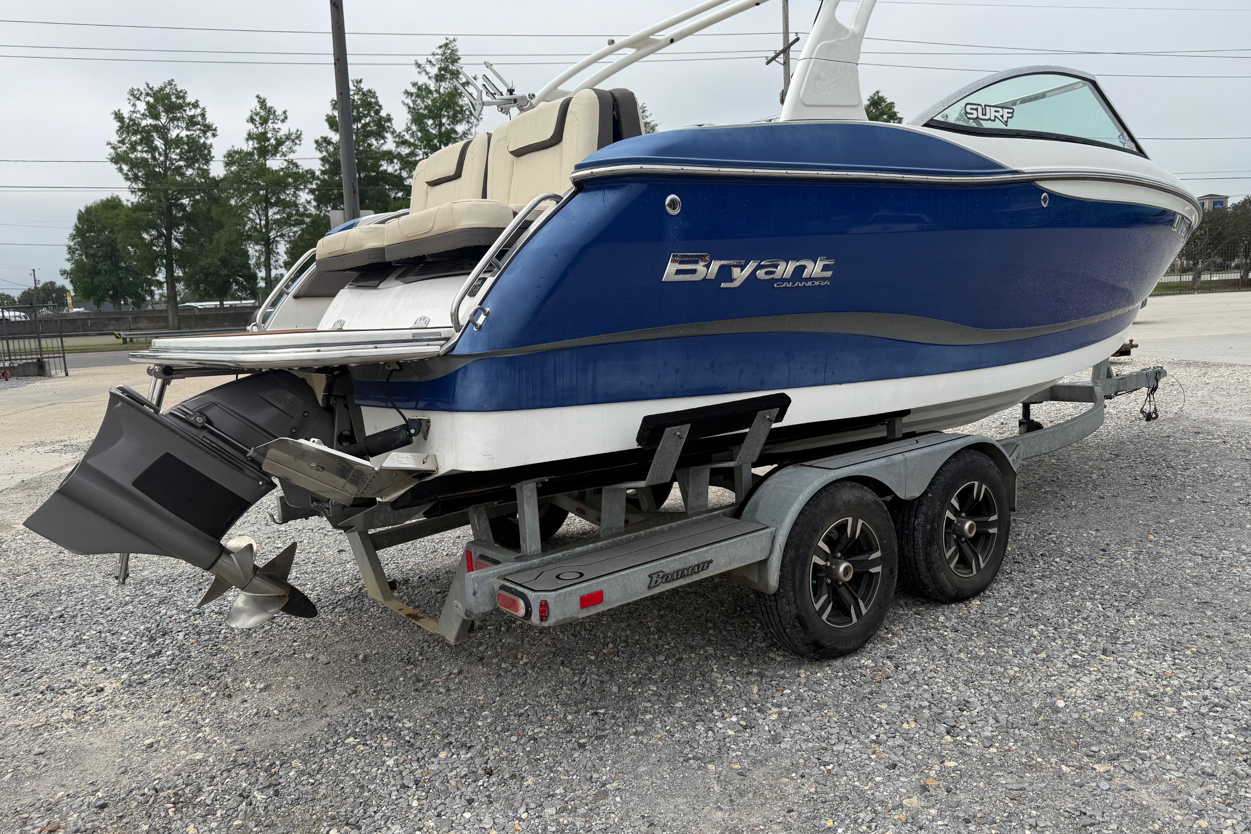 Blue 2018 Bryant Calandra boat on trailer, parked on gravel lot.