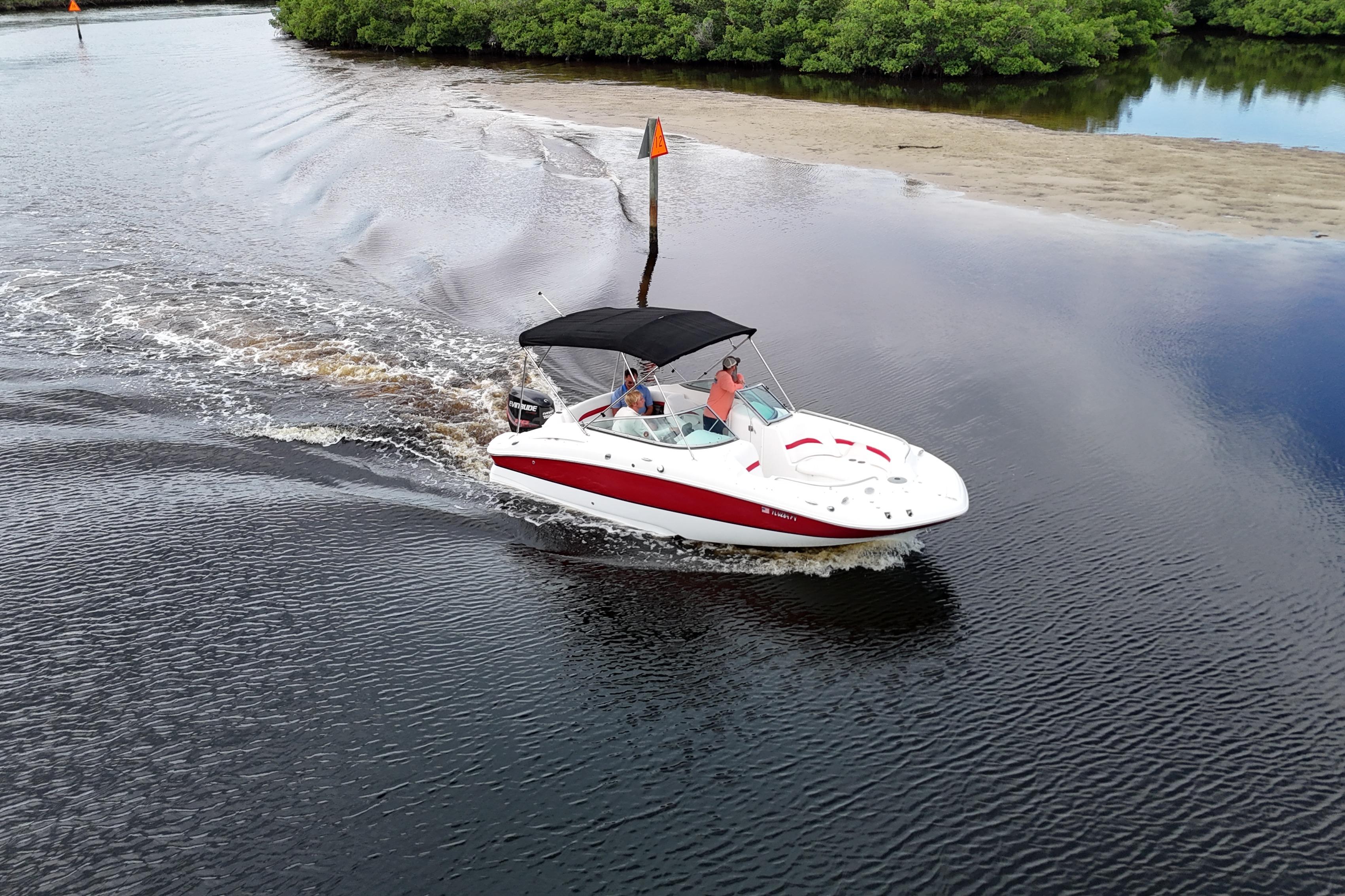 2015 Hurricane SunDeck 2200 OB cruising on a calm river with lush greenery.
