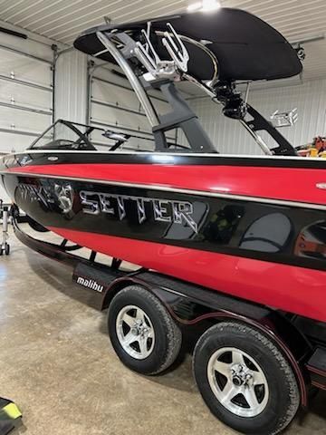 A red 2009 Malibu Wakesetter 23 LSV boat on a trailer in a garage.