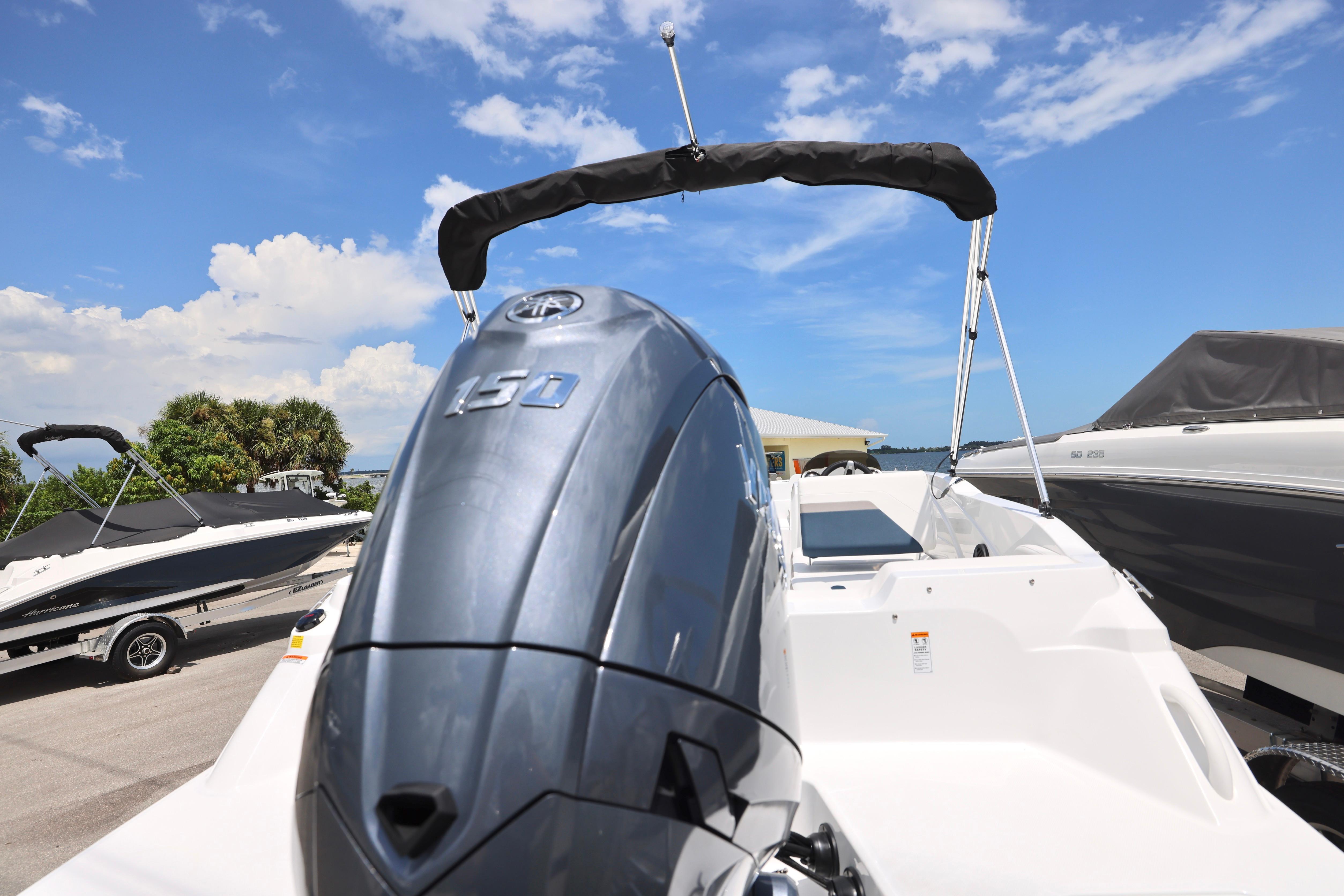 2026 Hurricane SunDeck Sport 205 OB boat with powerful outboard motor, parked under clear blue sky.