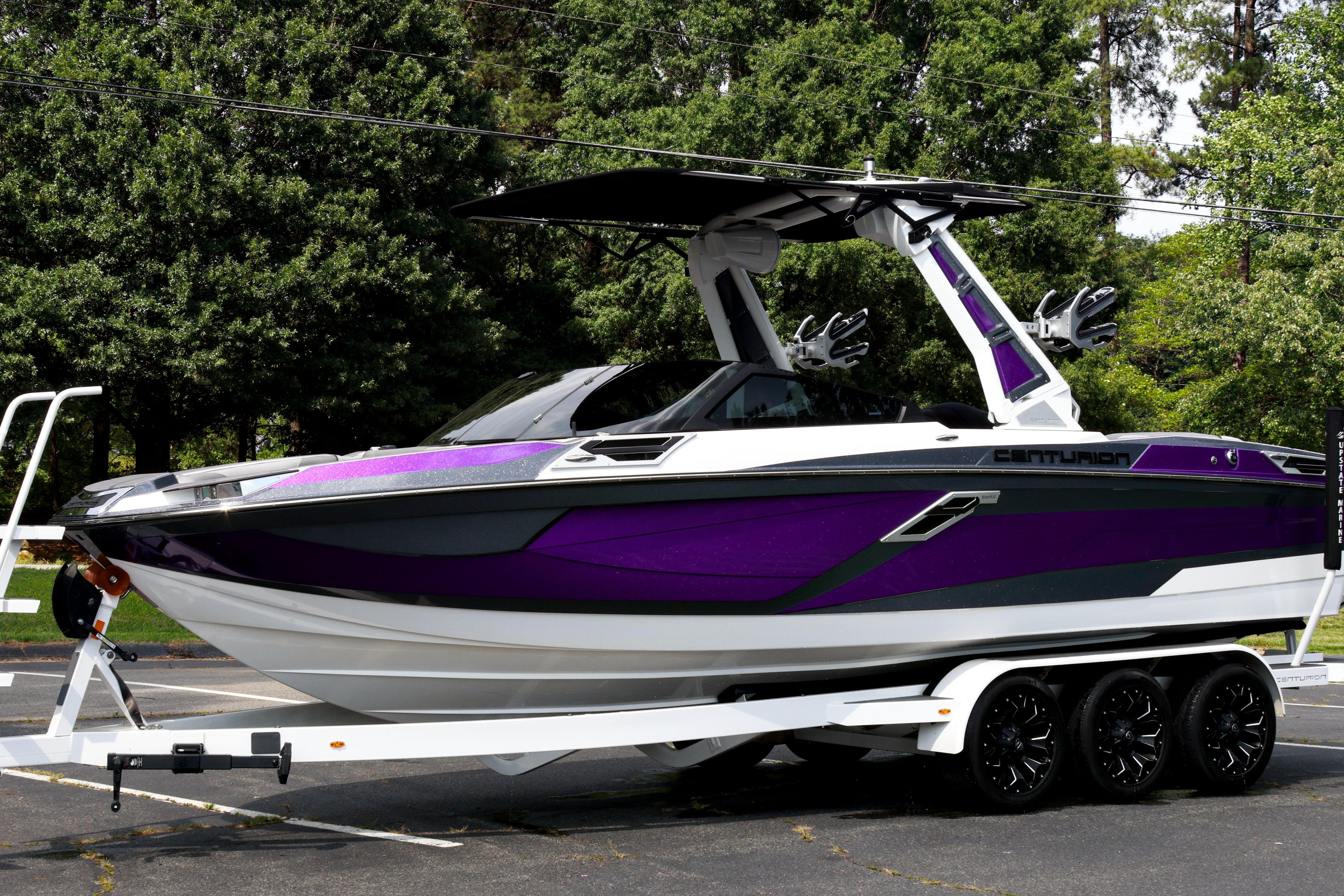 2022 Centurion Ri245 boat in vibrant purple on a trailer, parked outdoors.