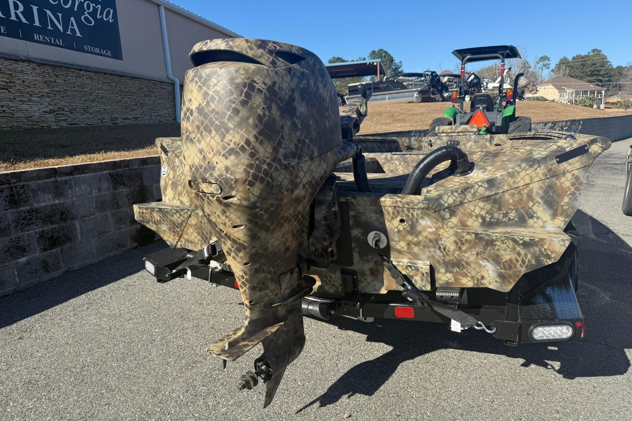 Camouflage-patterned Excel 183 Tomahawk boat, 2026 model, parked near a marina.