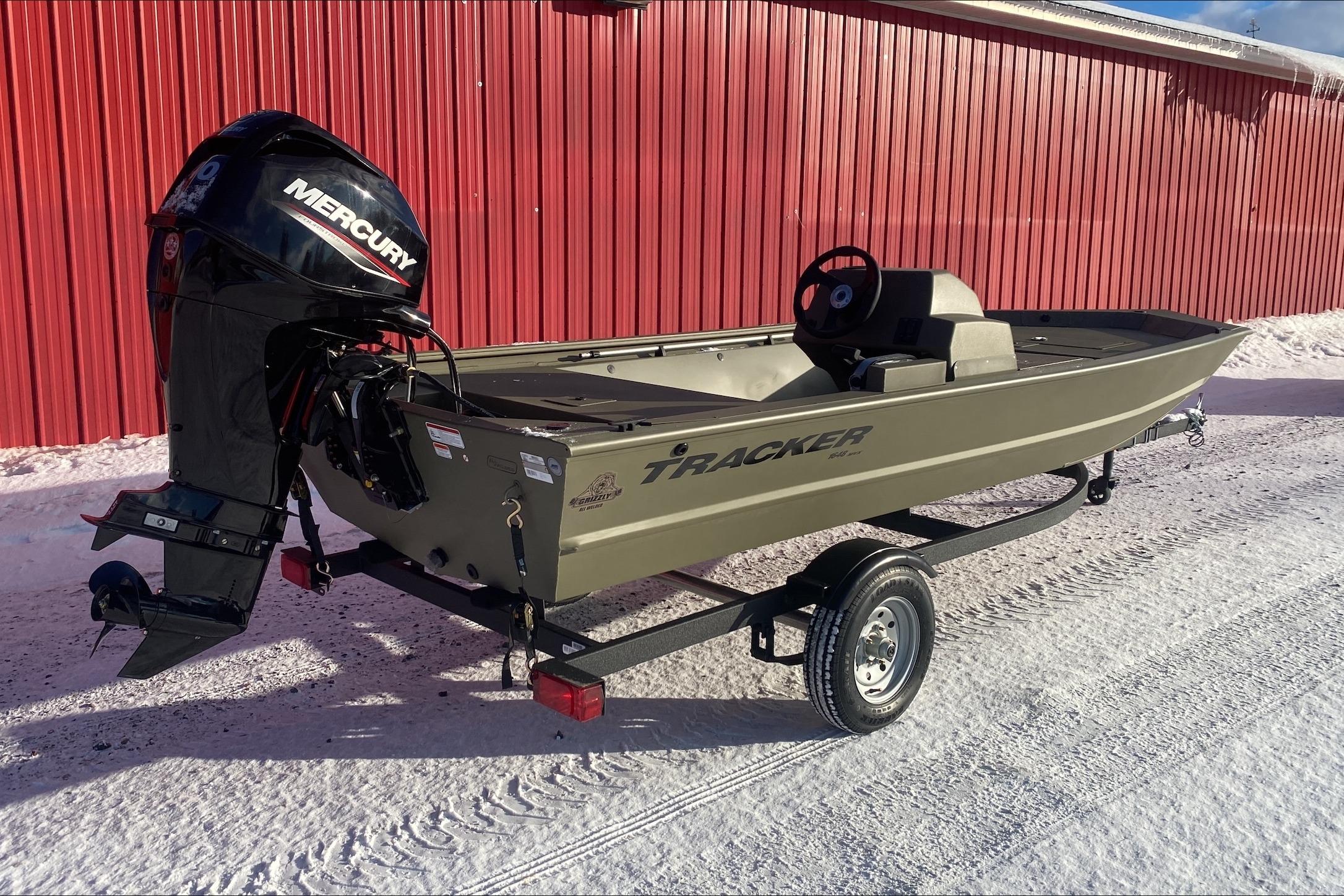 2026 Tracker Grizzly 1648 SC boat with Mercury engine, parked on snowy ground.