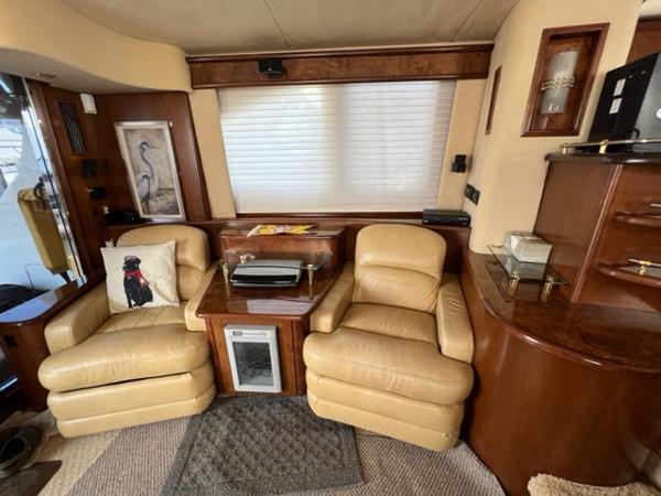 Luxurious 2009 Ovation 52 yacht interior with leather chairs and wooden cabinetry.