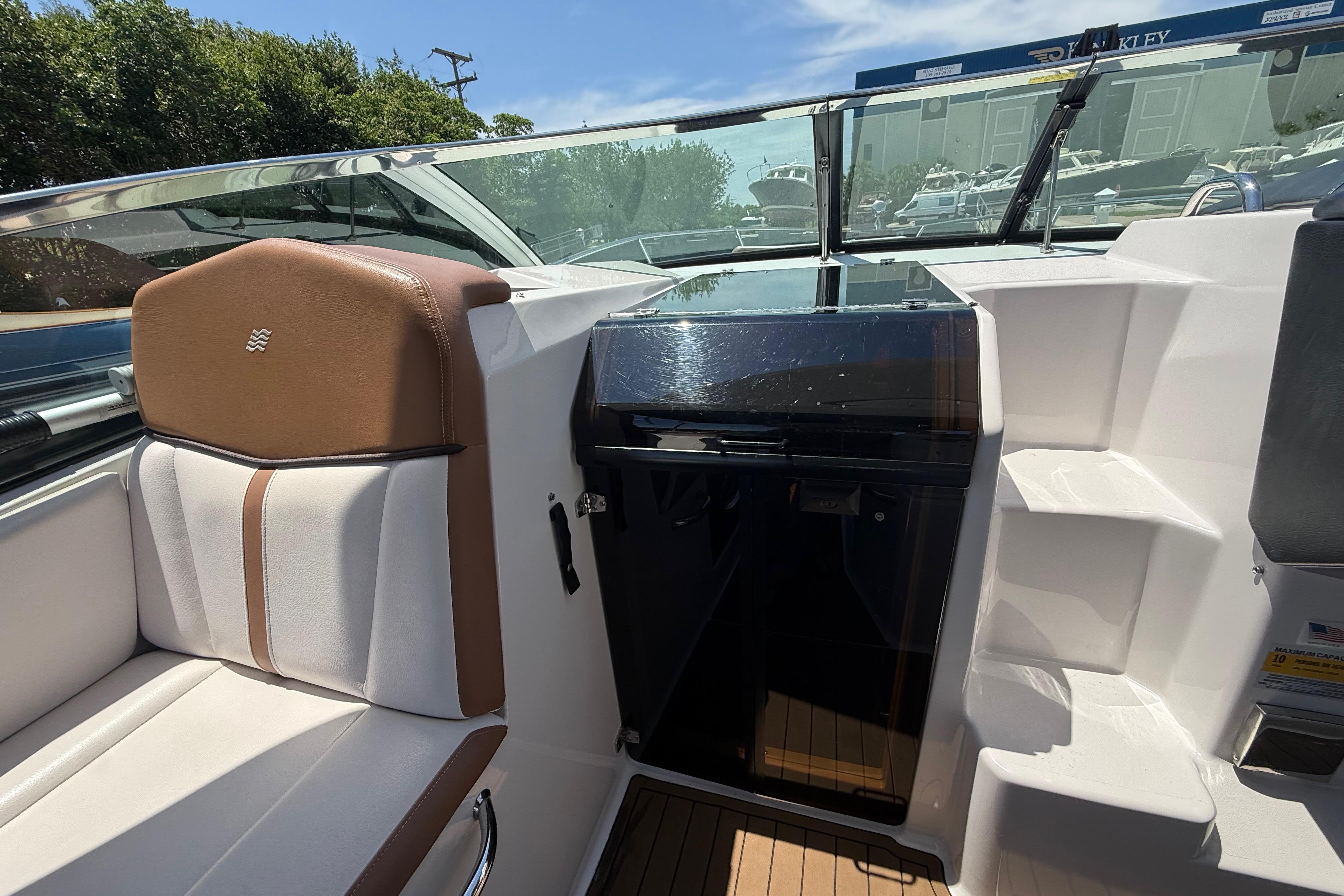 2017 Four Winns V275 boat interior with brown and white seating, sleek dashboard, and steps.