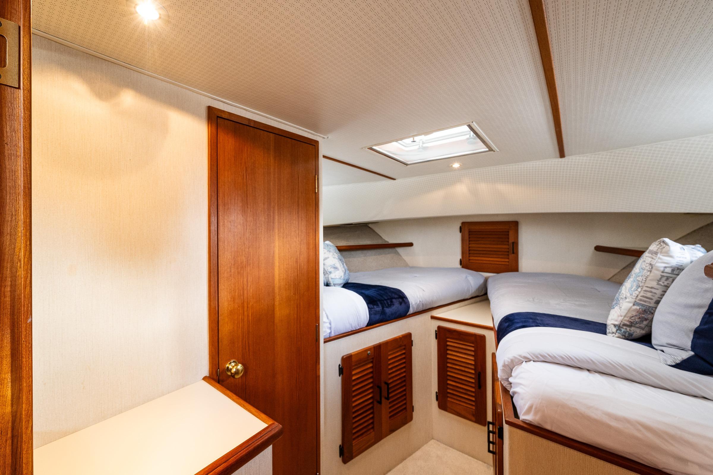 Interior of 1991 Tollycraft 48 Cockpit Motor Yacht with cozy twin beds and wooden accents.