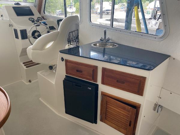 Interior of the 2015 Eastern 27 Islander with helm, seat, sink, and cabinetry.