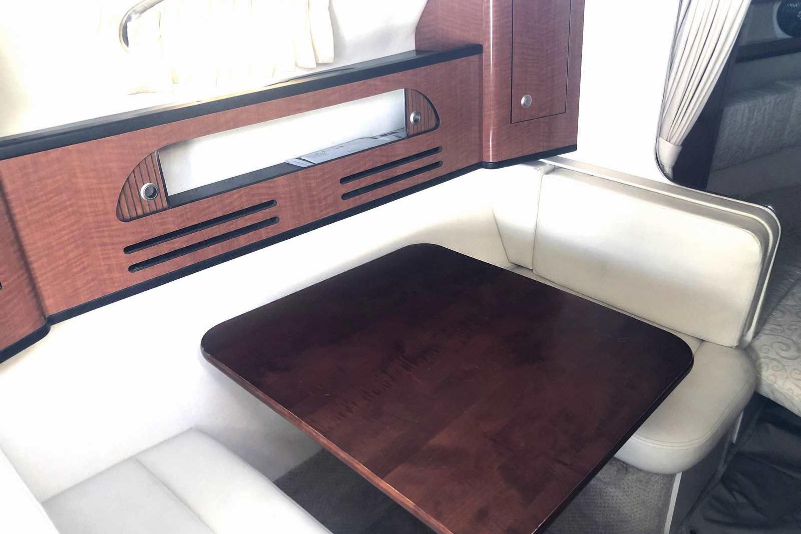 Interior of 2005 Sea Ray 280 Sundancer with wooden table and cushioned seating.