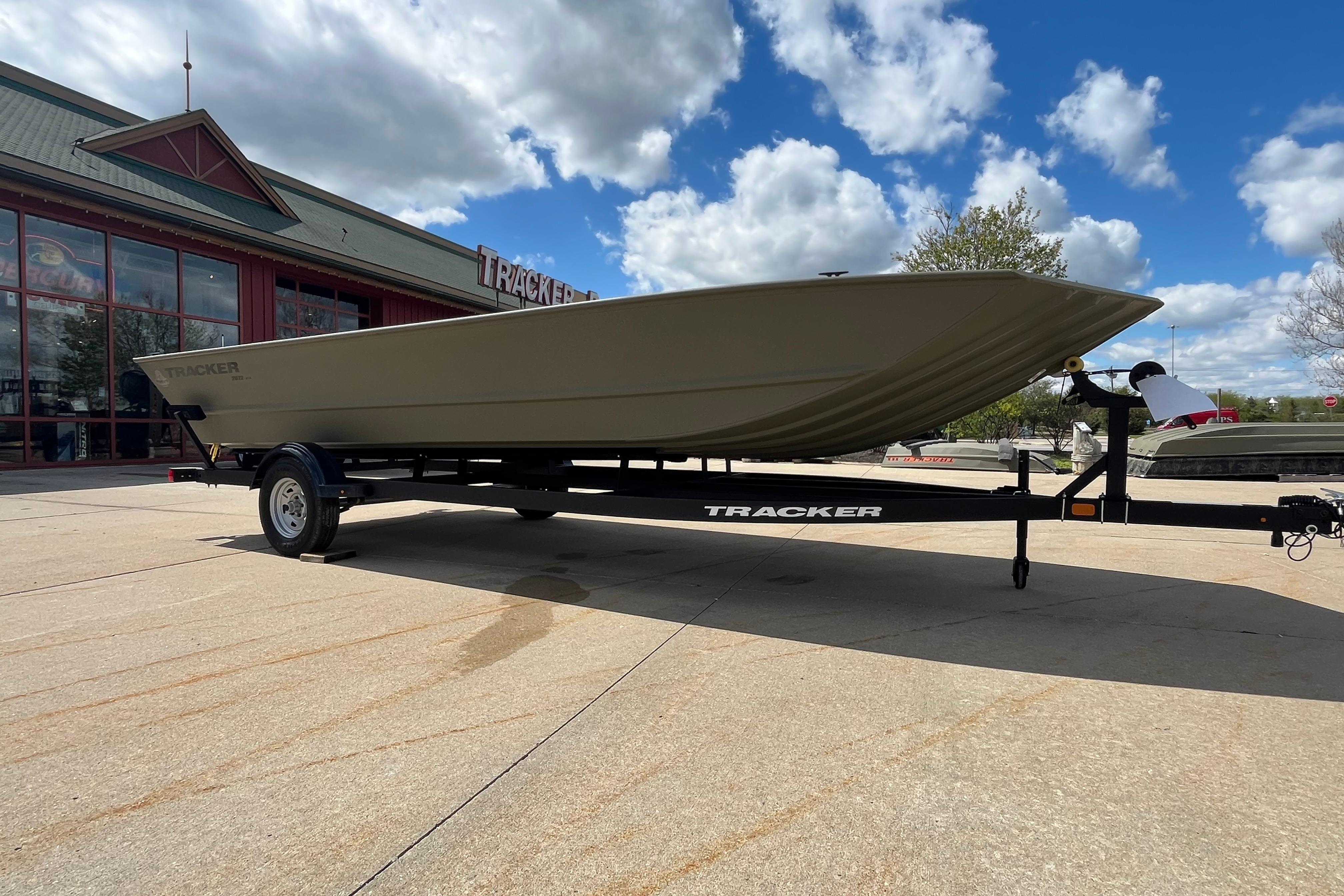 2026 Tracker Grizzly 2072 Utility boat on trailer, parked outside dealership under blue sky.