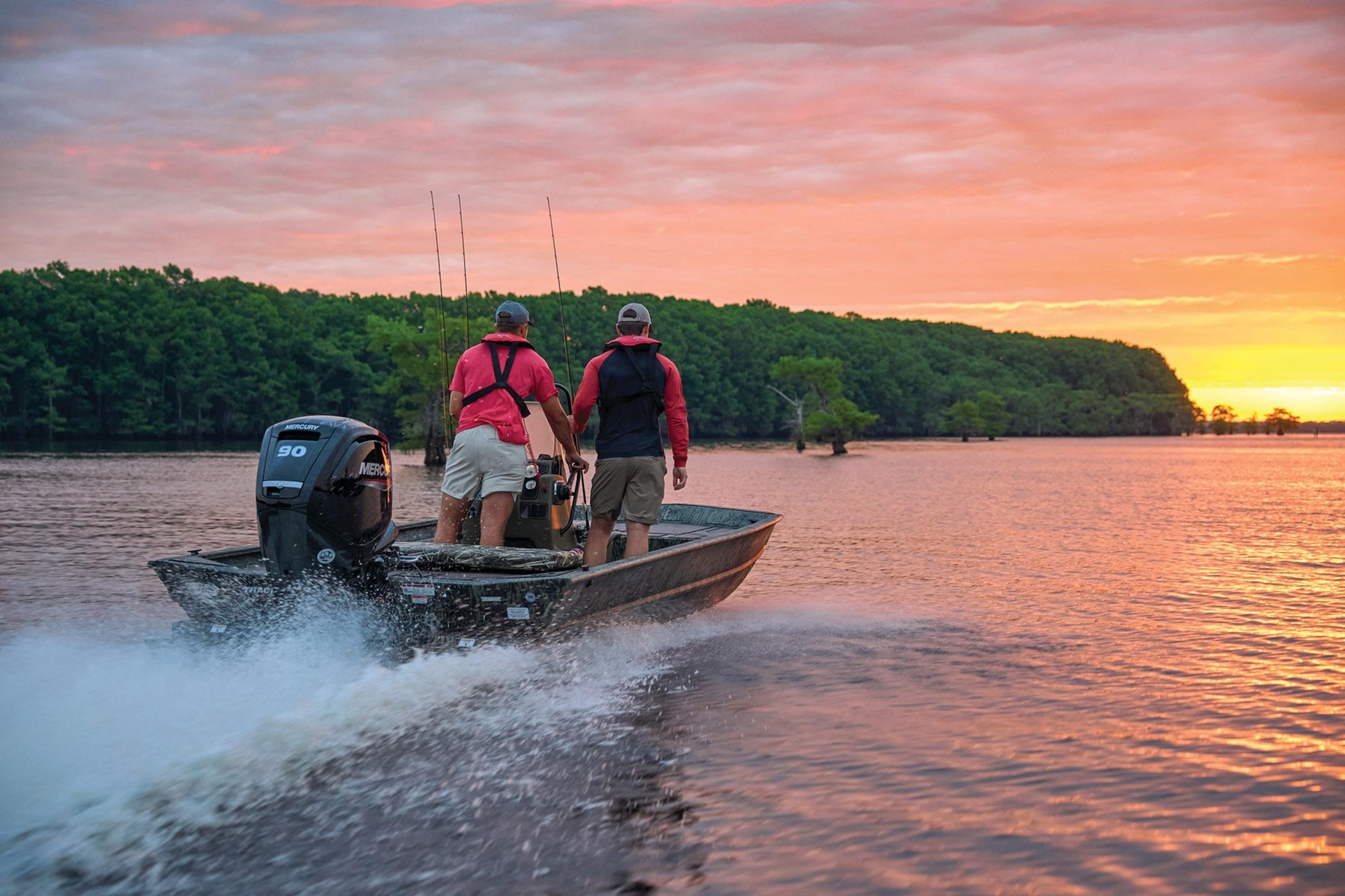 Two people on a 2026 Tracker Grizzly 1860 CC boat at sunset on a lake.