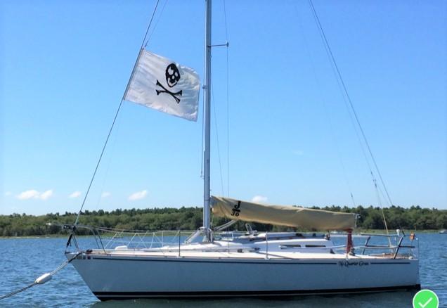 1979 J Boats J 30 sailboat with pirate flag on calm water.