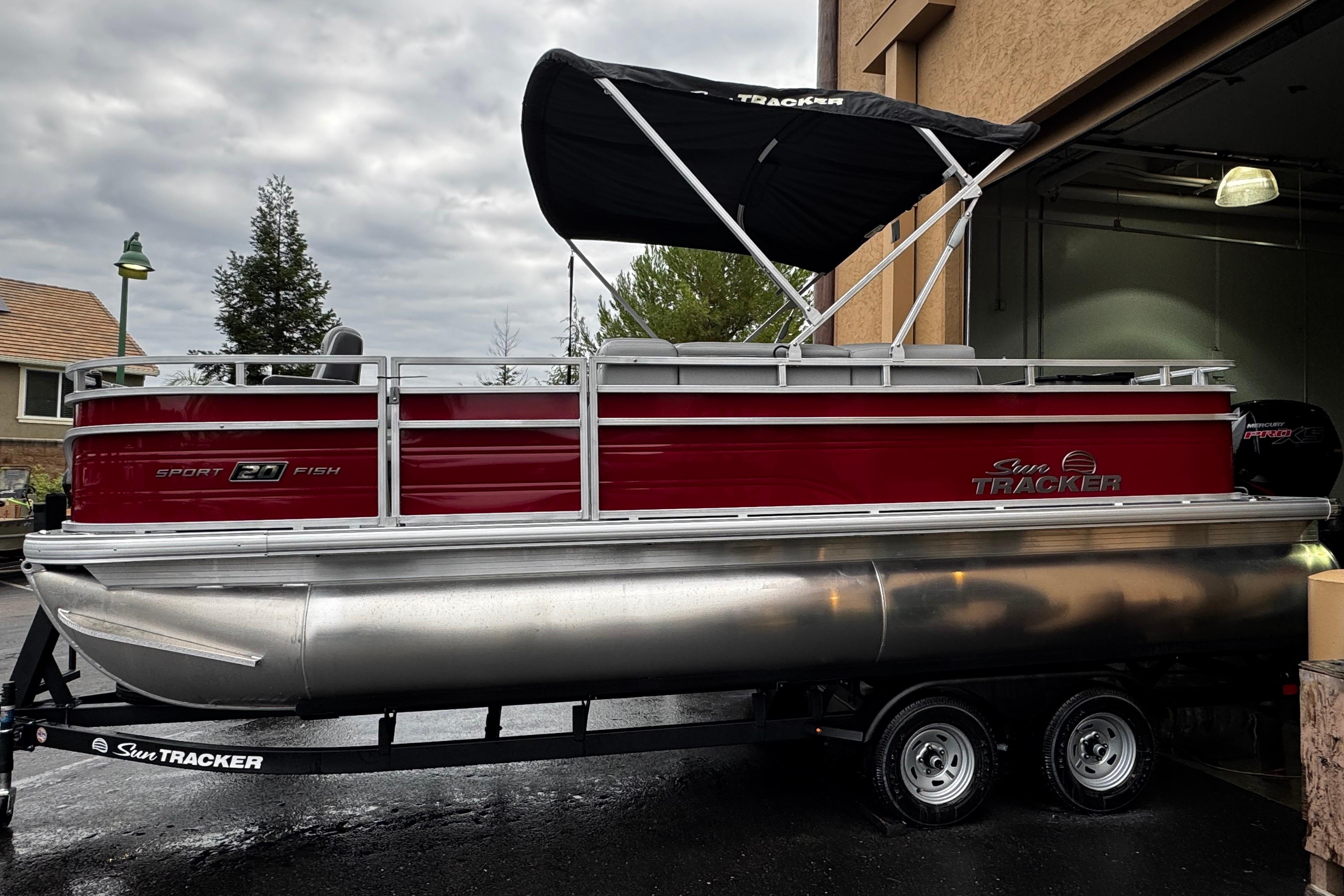 2026 Sun Tracker SportFish 20 DLX pontoon boat with red exterior and black canopy.