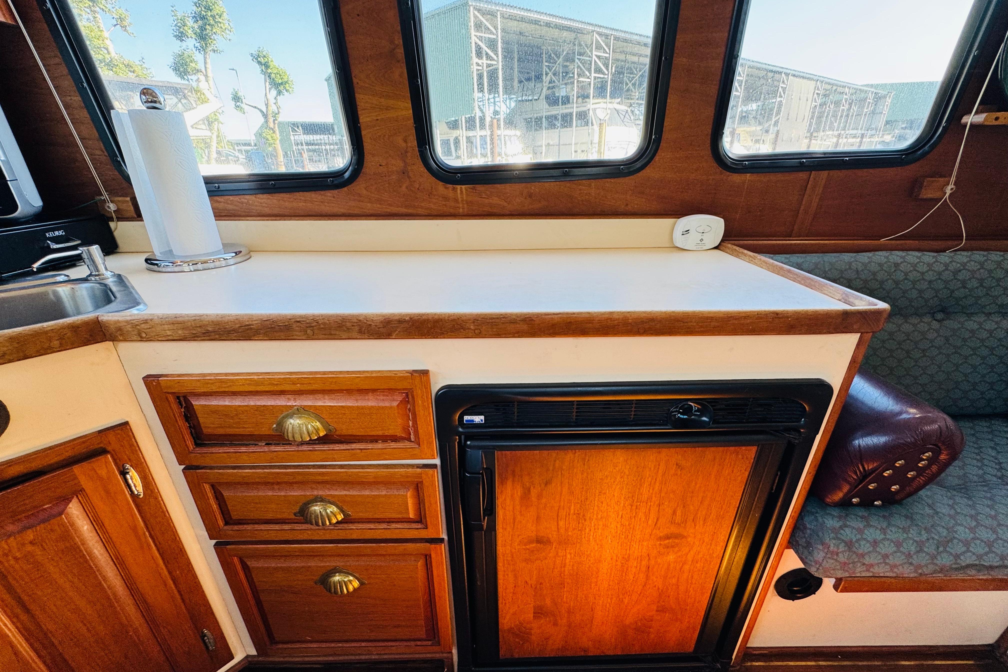 Interior of a 1996 Nordic Tug 32 with wooden cabinetry and compact kitchen area.