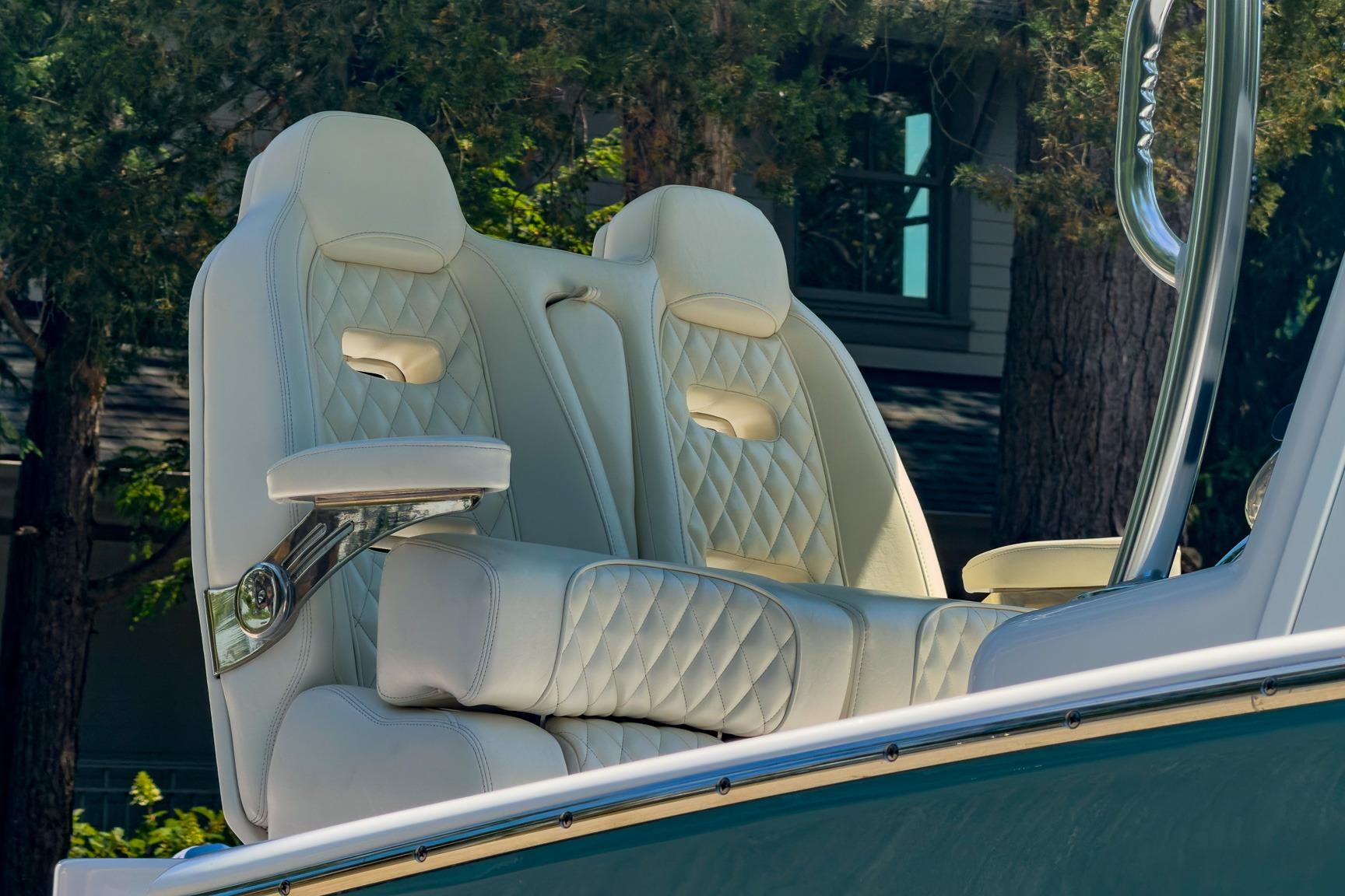 Luxurious white leather seats on a 2025 Weaver 25 boat, surrounded by trees.