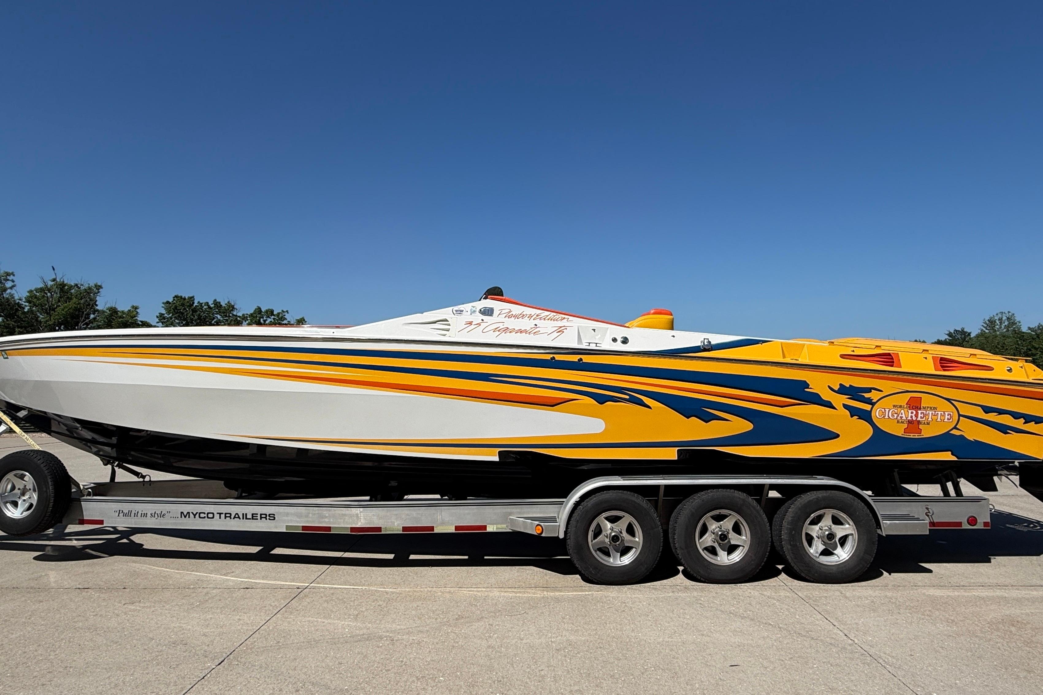 2002 Cigarette 35' Cafe Racer boat on trailer, vibrant yellow and blue design.