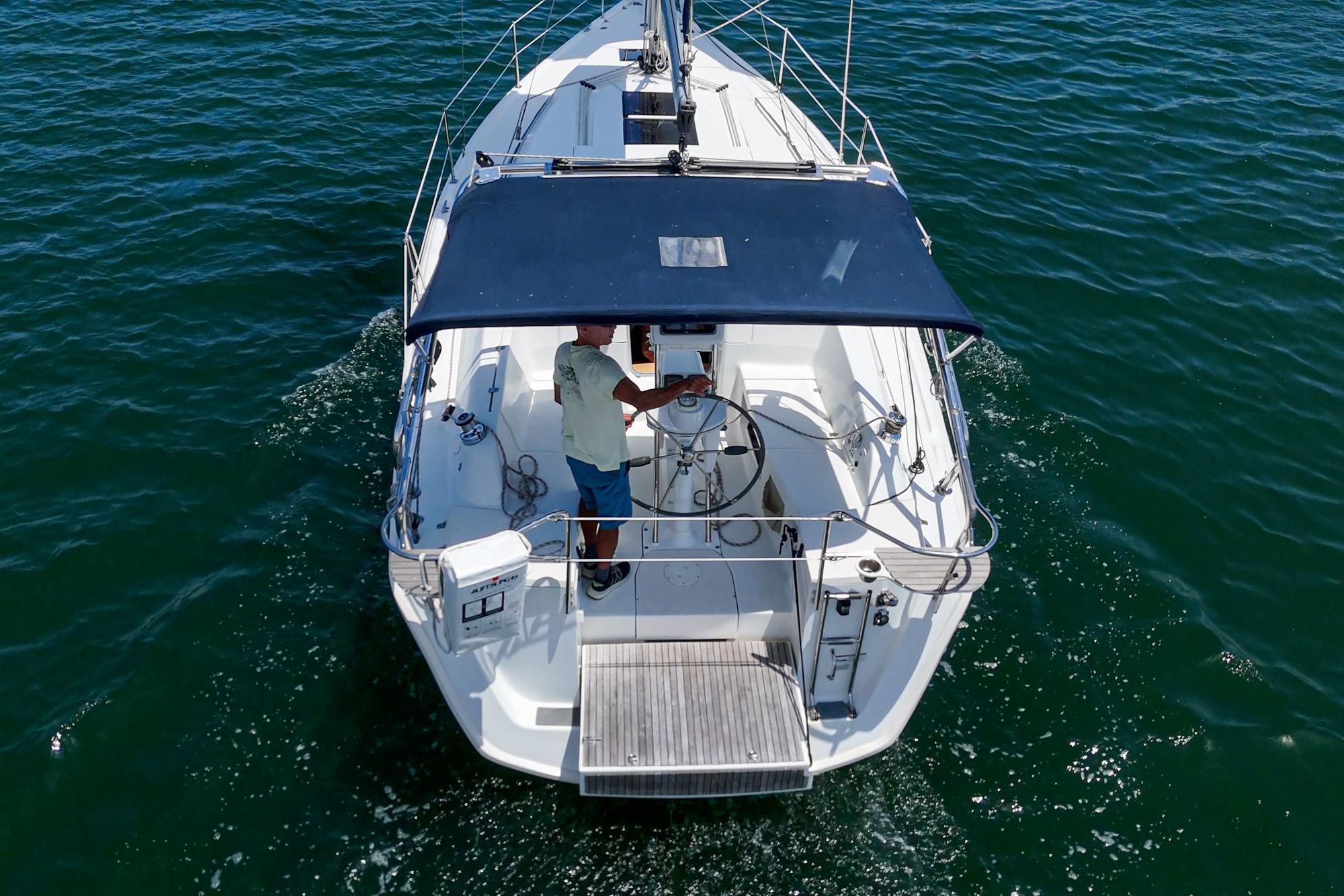 2015 Hunter 33 sailboat on open water, viewed from above, with a person steering.