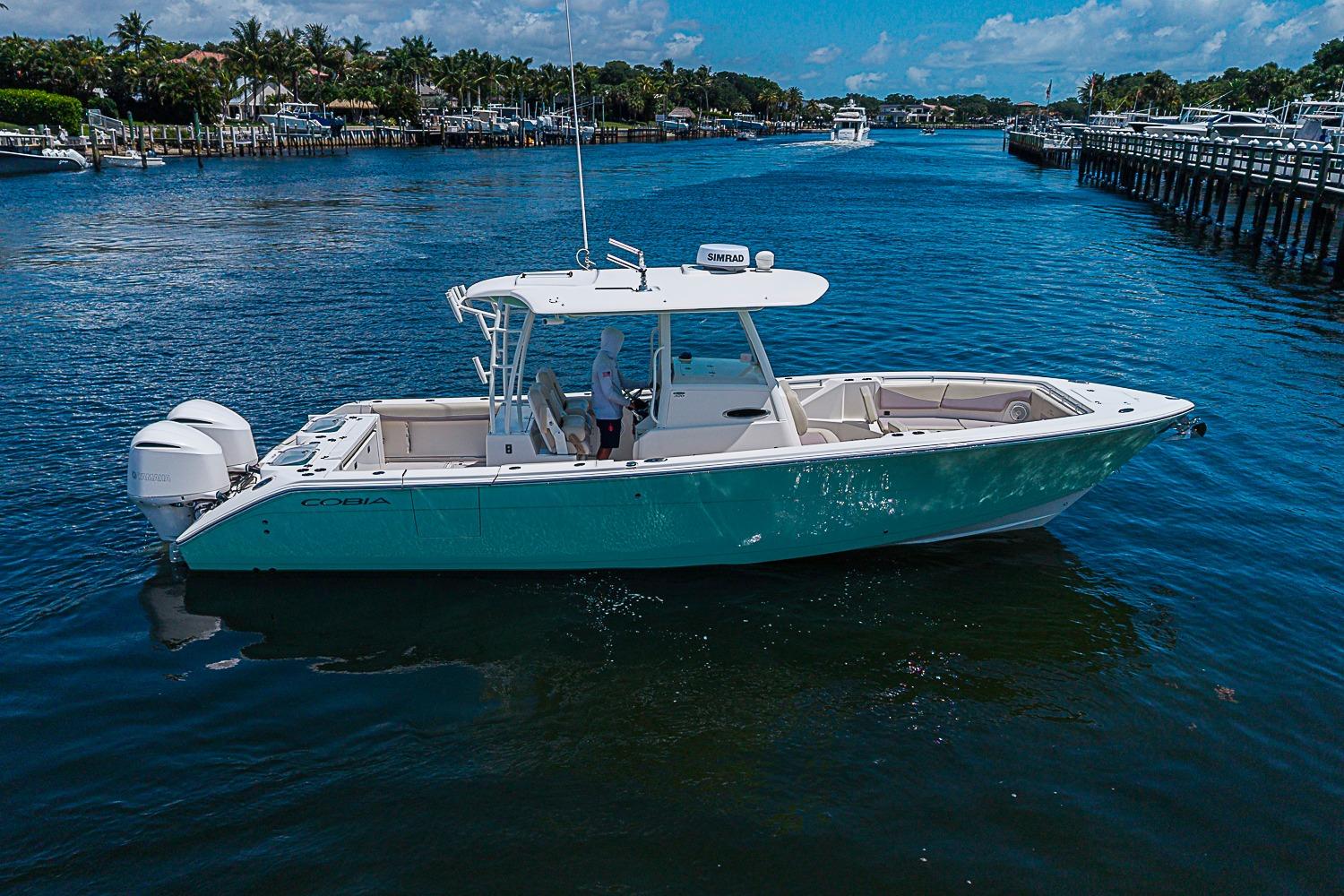 2019 Cobia 320 Center Console boat cruising on a sunny day in a scenic waterway.