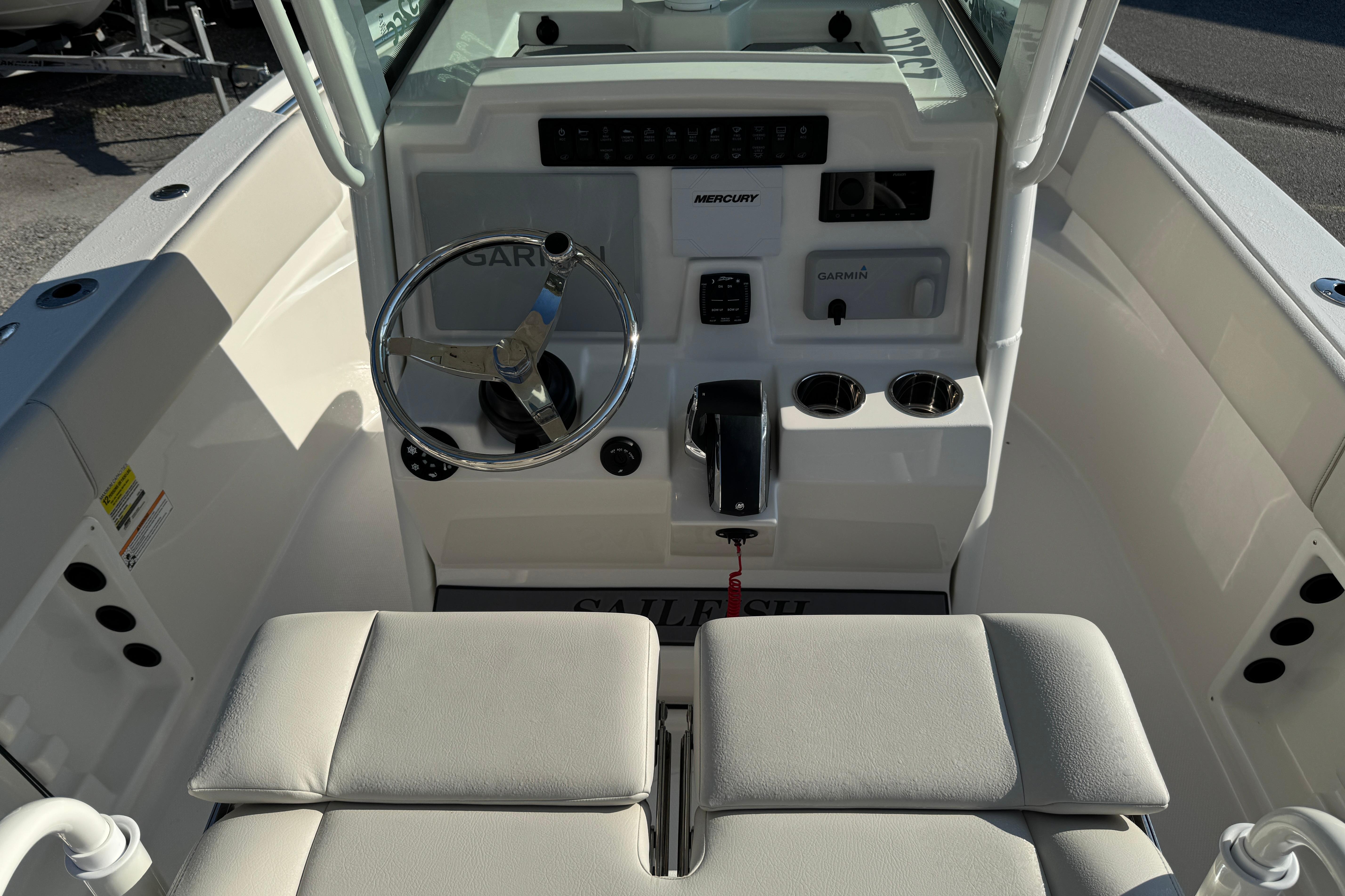 2026 Sailfish 232 CC boat cockpit with steering wheel, controls, and cushioned seating.