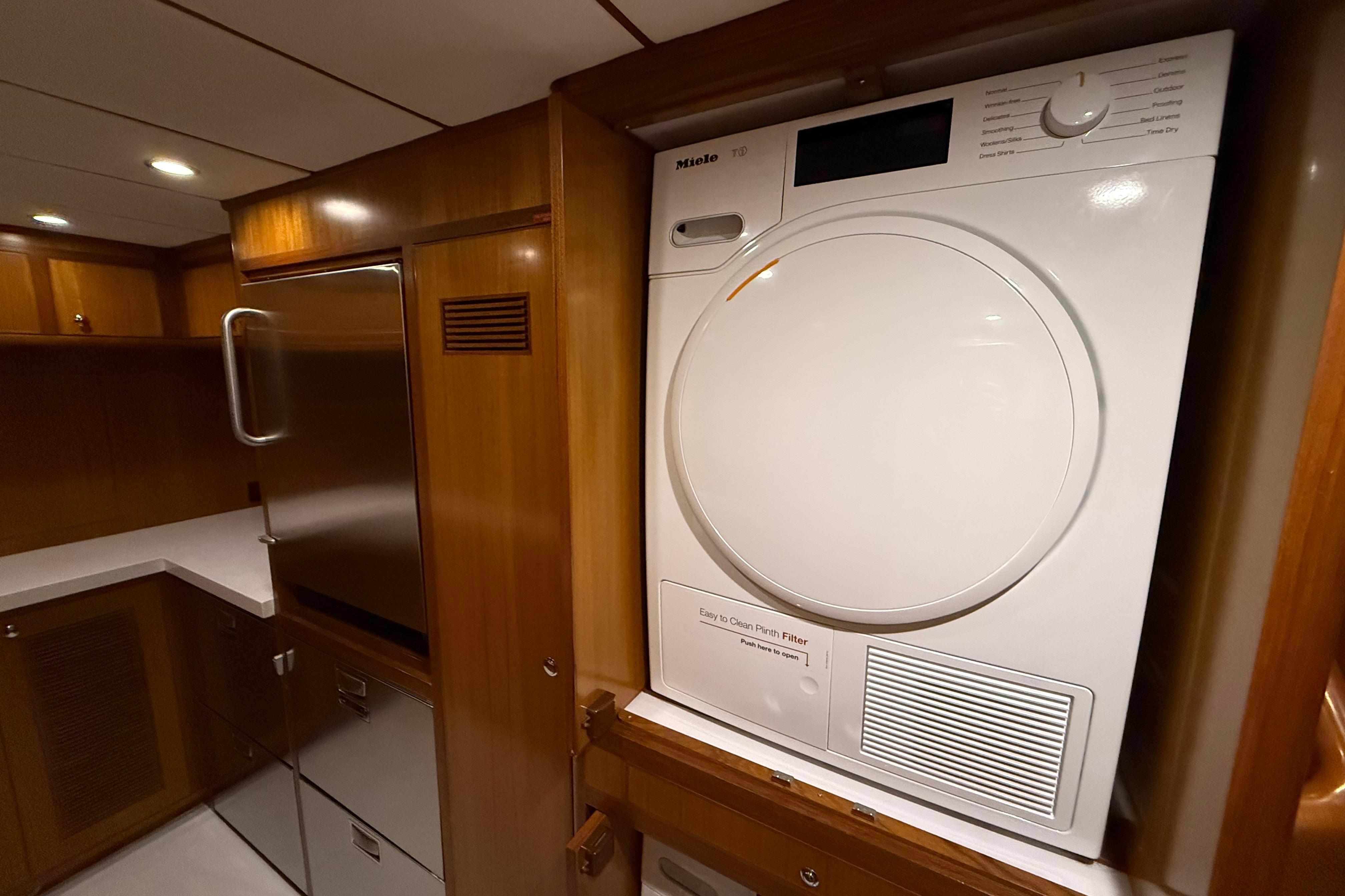 Laundry area in 2009 Nordhavn N64 yacht with Miele dryer and wooden cabinetry.