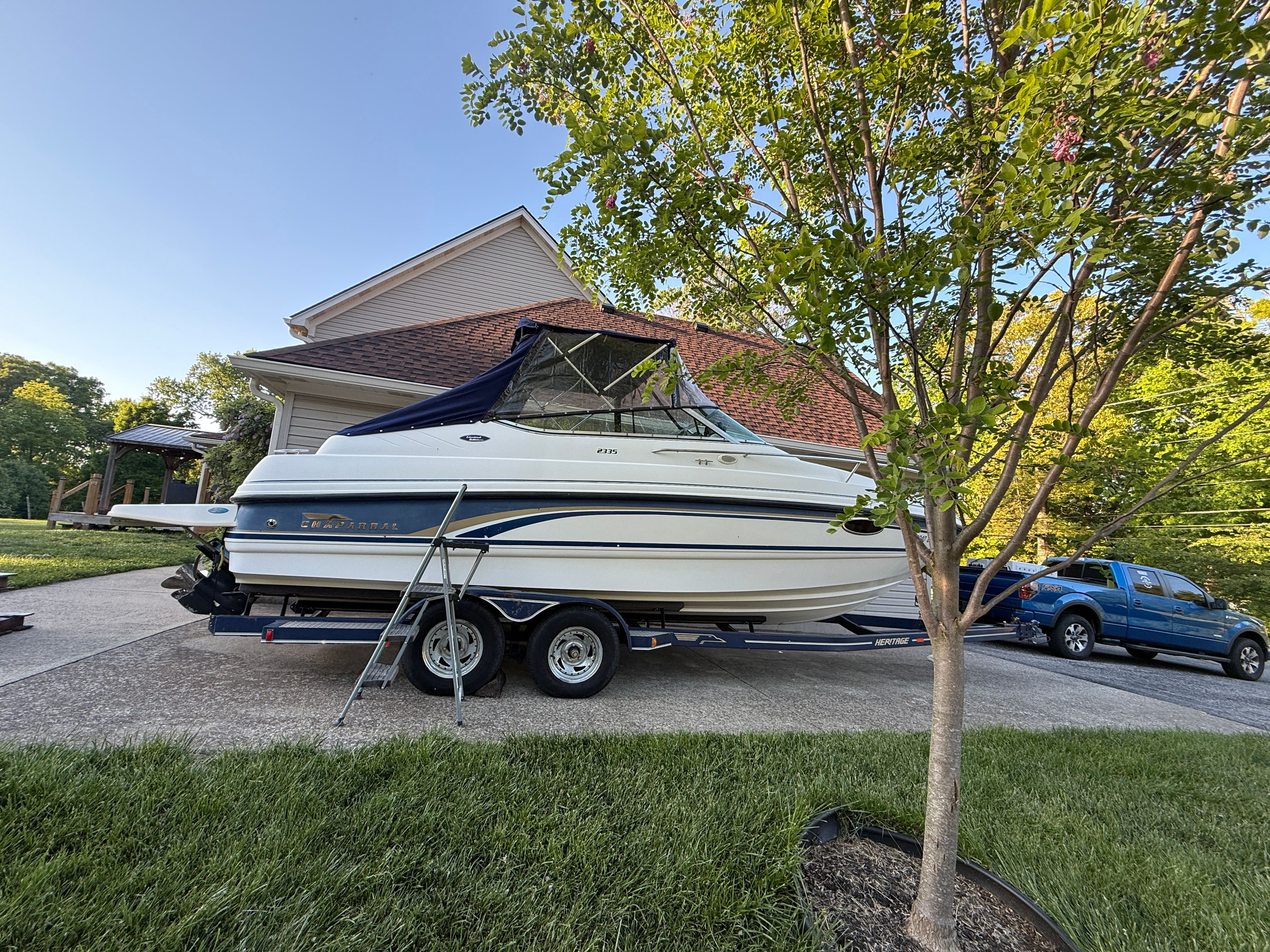 1999 Custom 2335 Cuddy cabin boat on trailer in driveway.