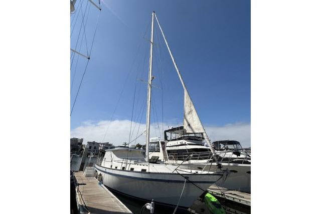 1982 Lancer 45 Motorsailer docked at marina under clear blue sky.