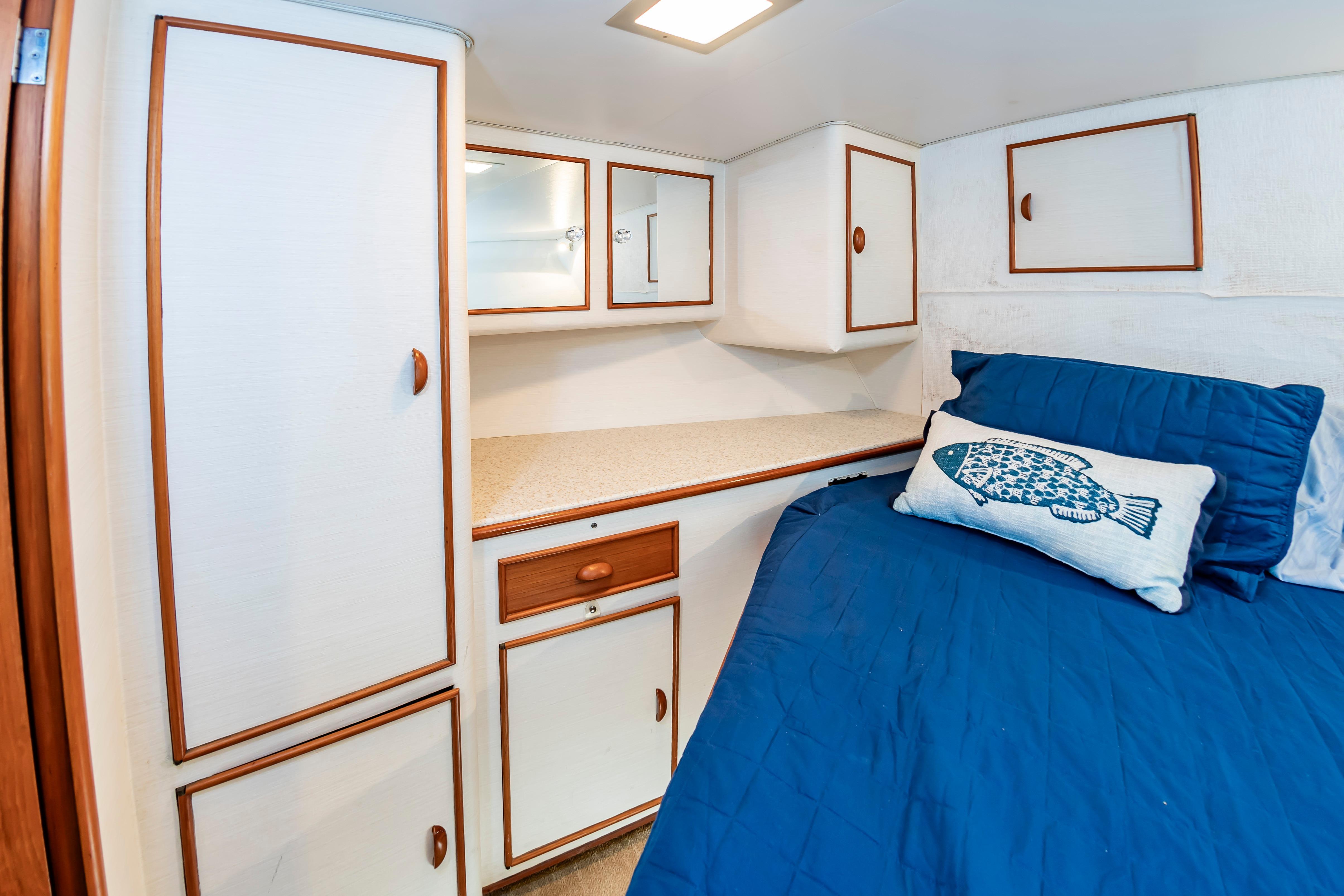 Cozy cabin interior of 1993 Custom Carolina Scarborough 56 Convertible with blue bedding and fish pillow.