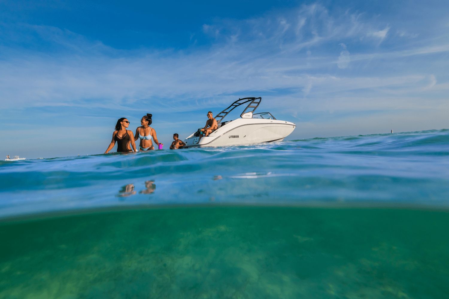 A group of people enjoying the water beside a Yamaha 222SD boat.