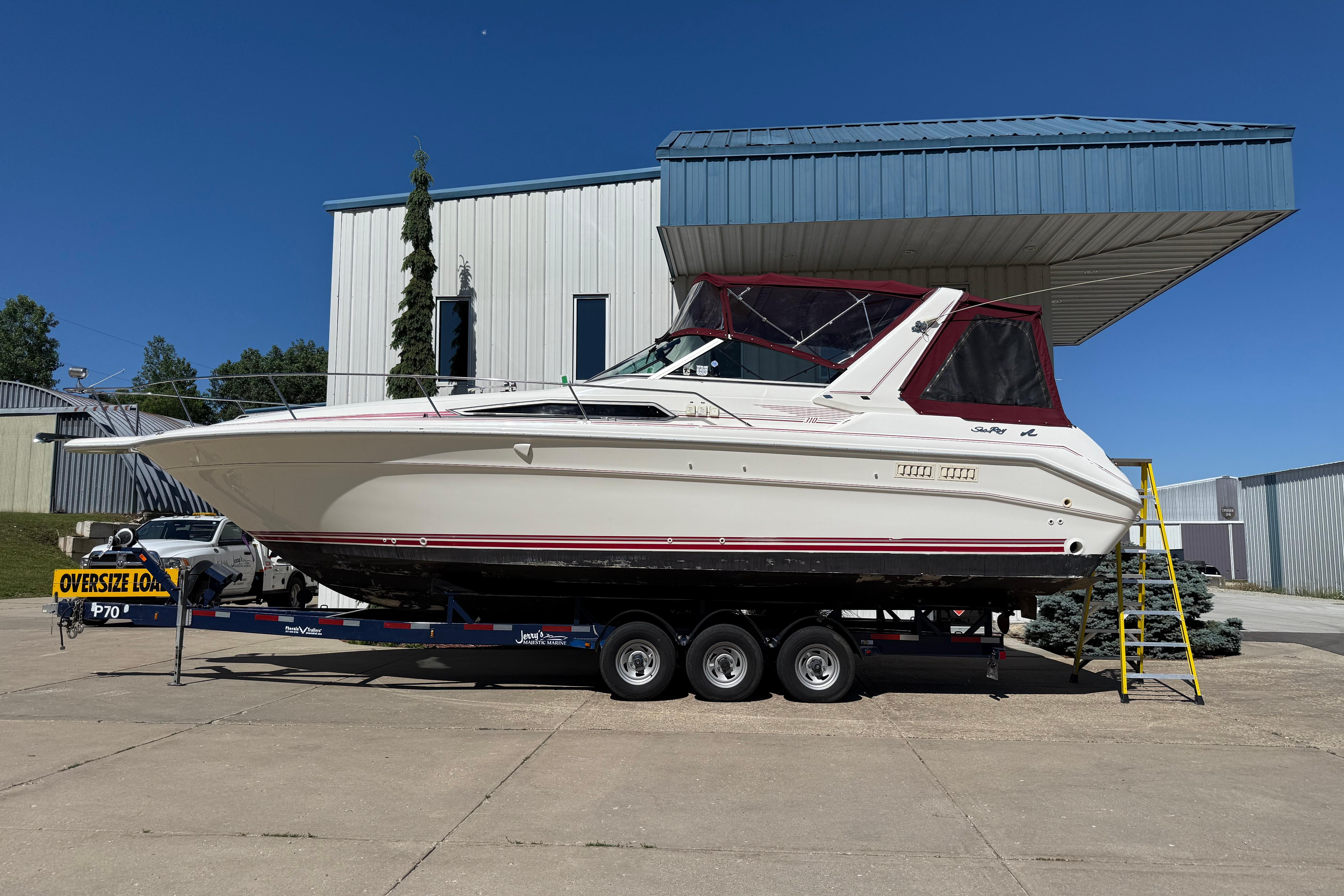1990 Sea Ray 310 Express Cruiser on trailer, parked outdoors under clear blue sky.