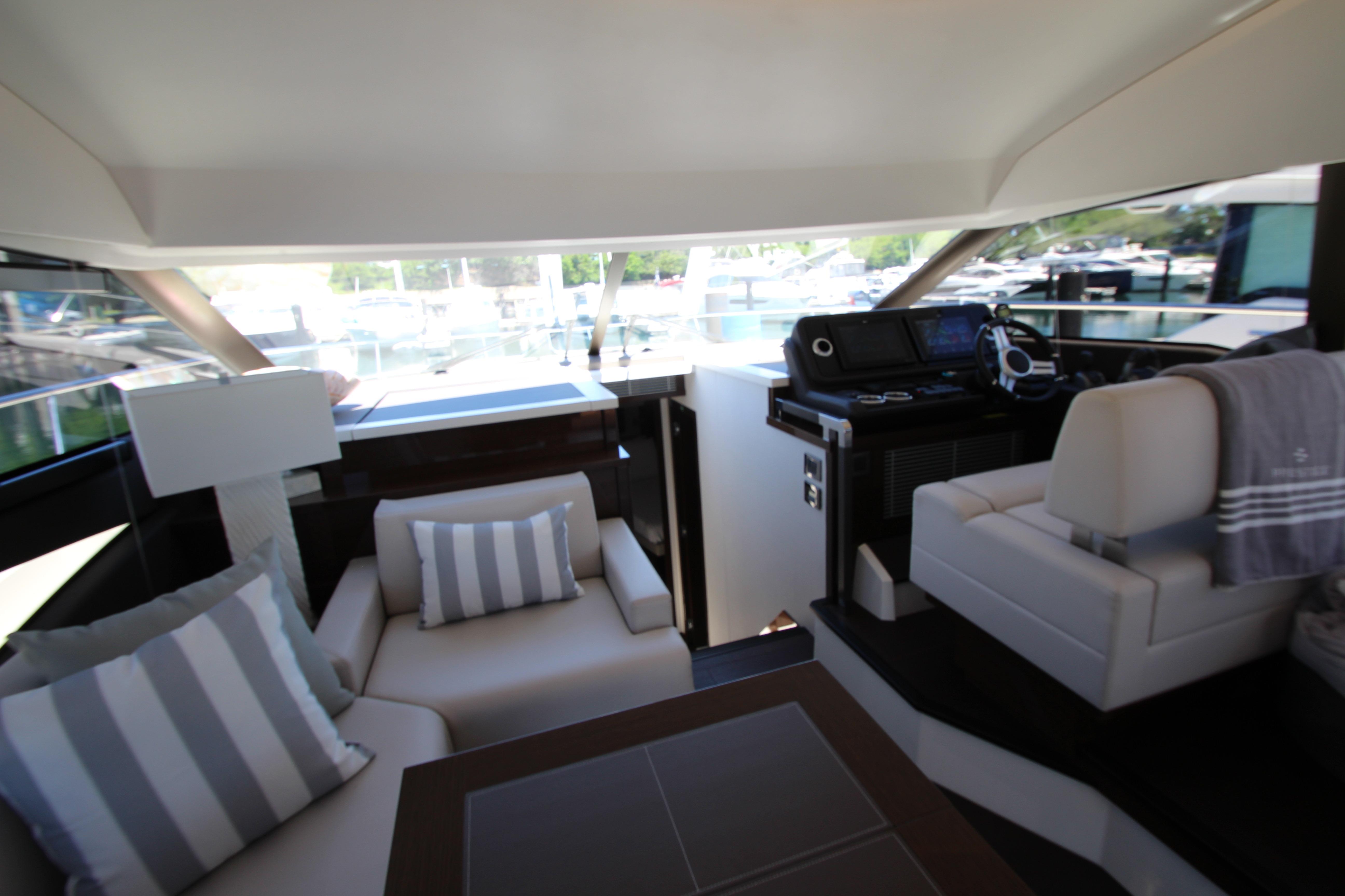 Luxurious interior of 2022 Prestige 520 yacht with modern seating and helm station.