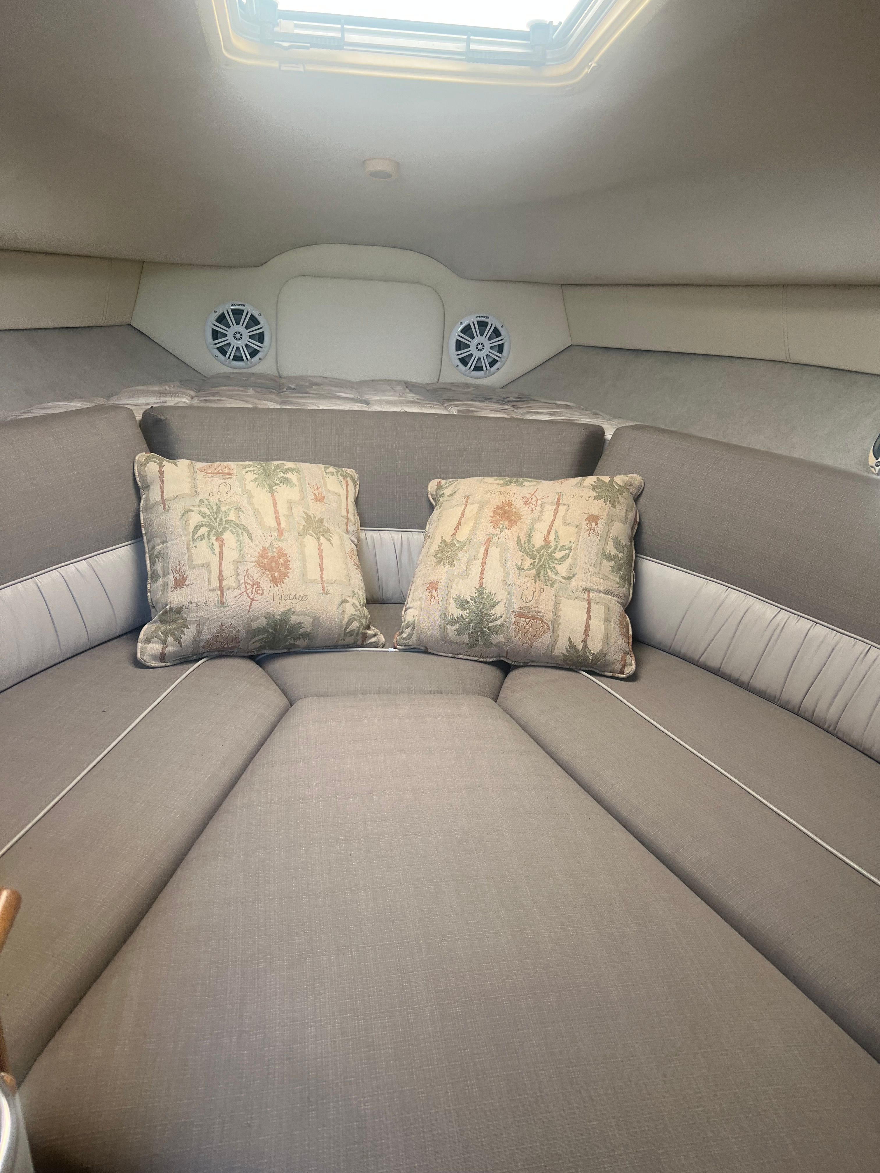 The image shows a boat interior with gray upholstery and two decorative pillows.