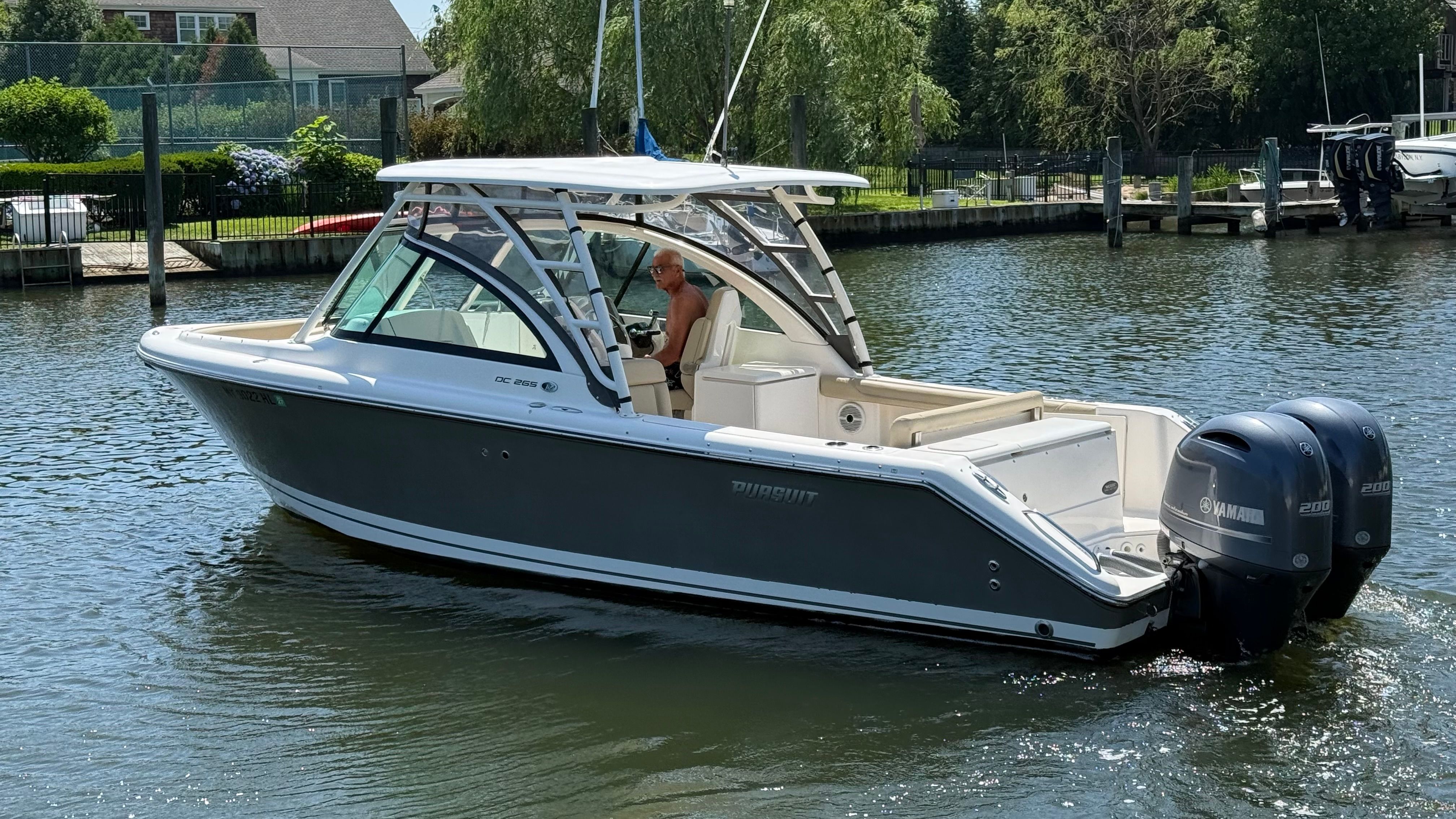 A 2016 Pursuit DC 265 Dual Console boat cruising on calm water.