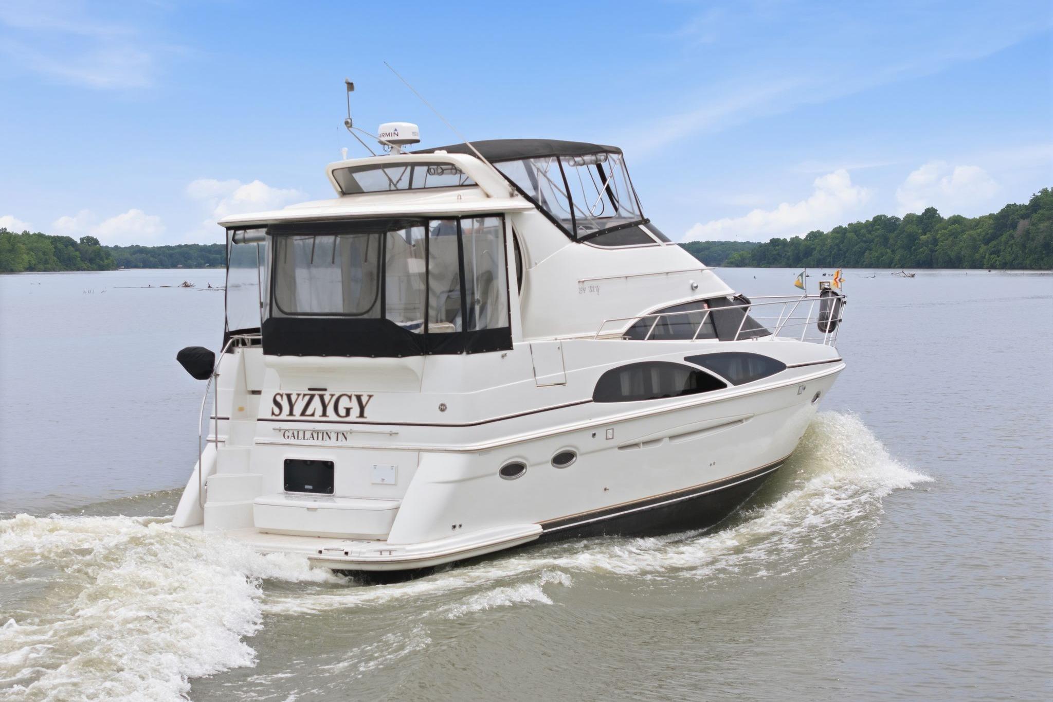 2005 Carver 39 Motor Yacht cruising on a serene lake under a clear blue sky.