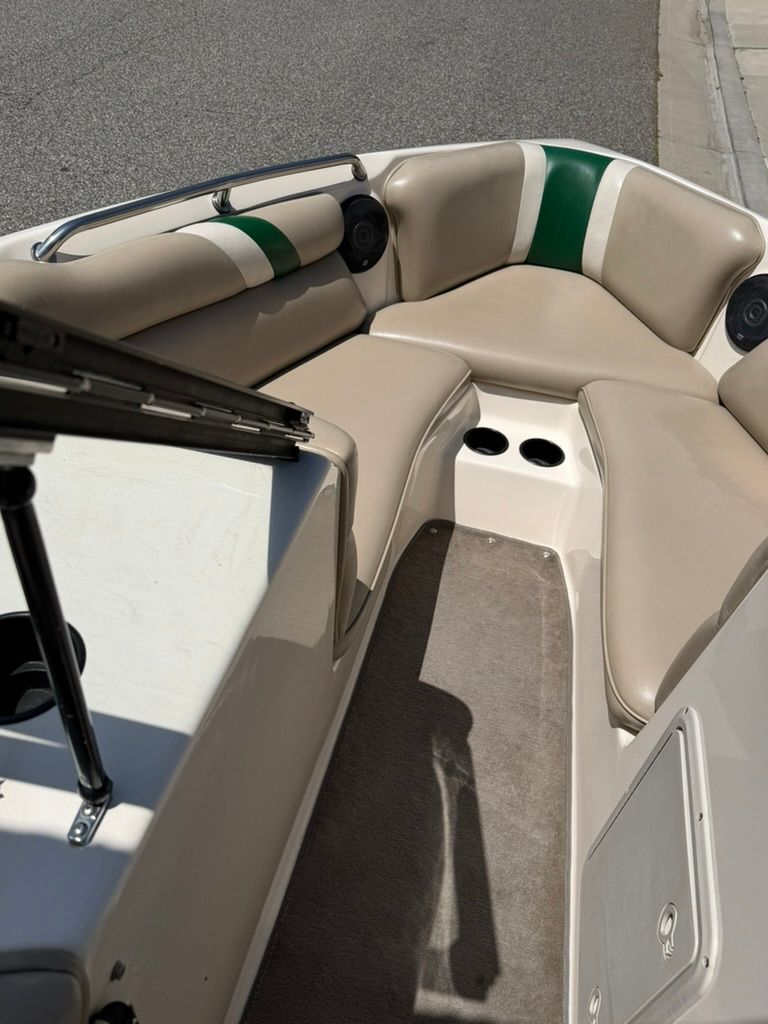 The boat features beige upholstery with green accents and a clean carpeted floor.