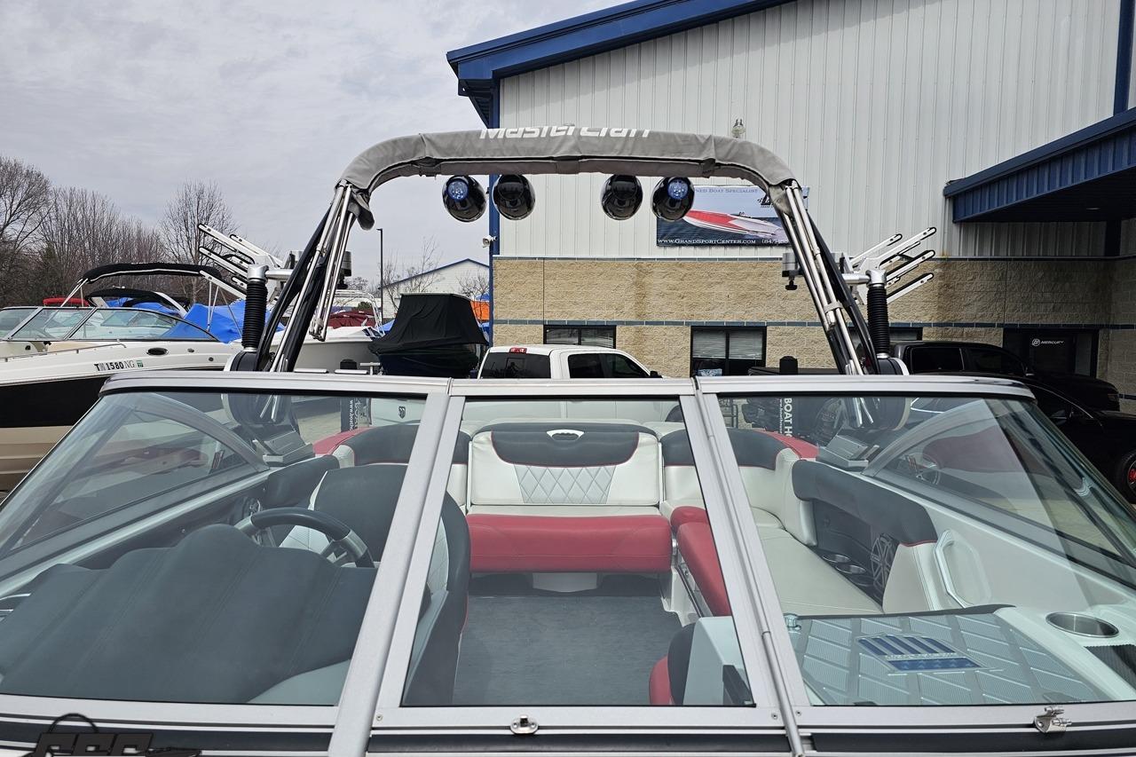 2013 MasterCraft X-10 boat with red and white interior, parked outdoors near a building.