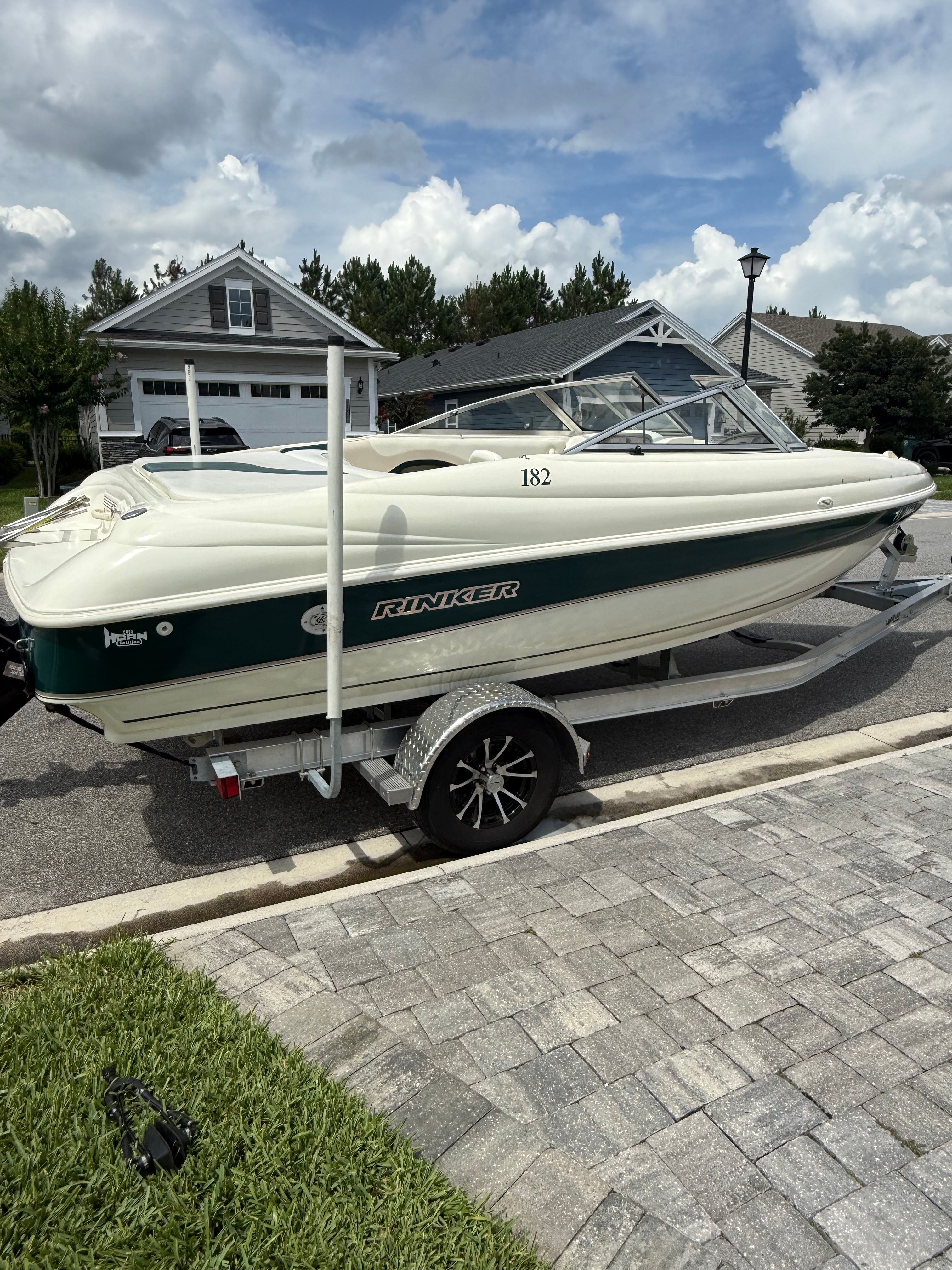 A 1998 Rinker Captiva boat on a trailer in a residential area.