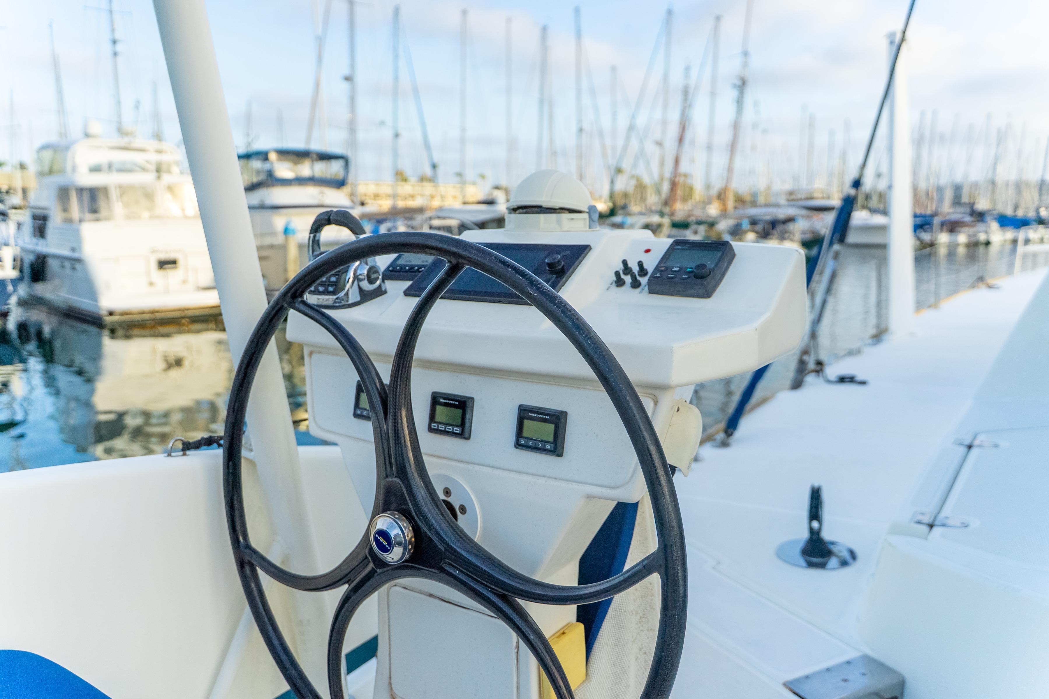 Steering wheel of a 2009 Catana 65 yacht docked in a marina.